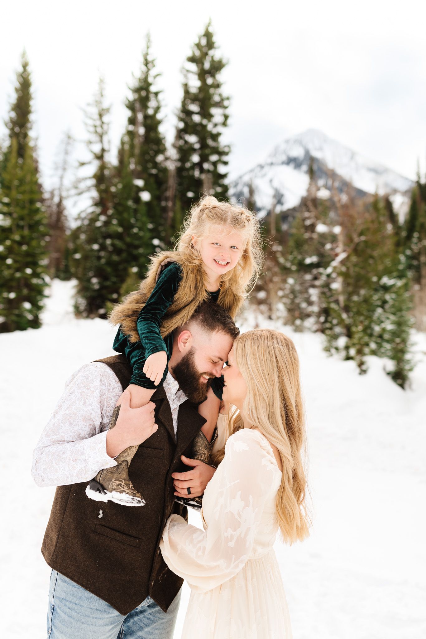 Playful family moments photographed in a scenic snow-covered mountain setting.