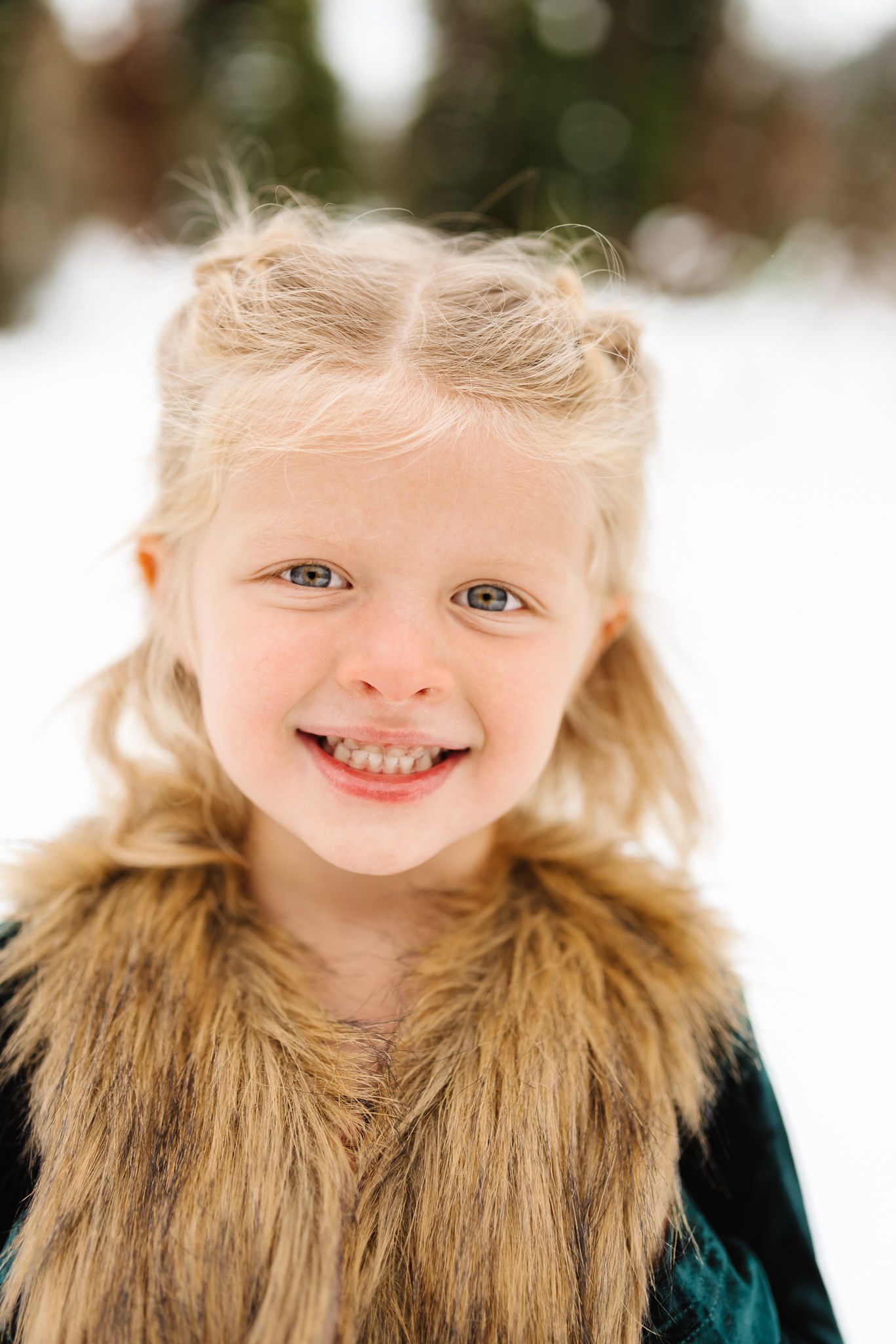 Close up portrait showing bright eyes and warm smile wearing a fur-trimmed coat in snowy setting in Jordan Pines in Big Cottonwood Canyon