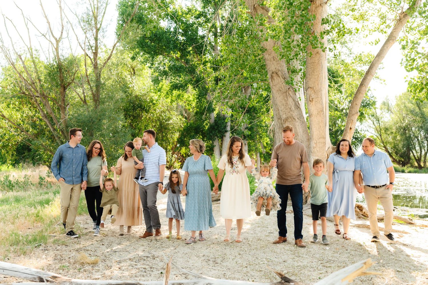 A large group gathered outdoors under tall trees on a sunny day.