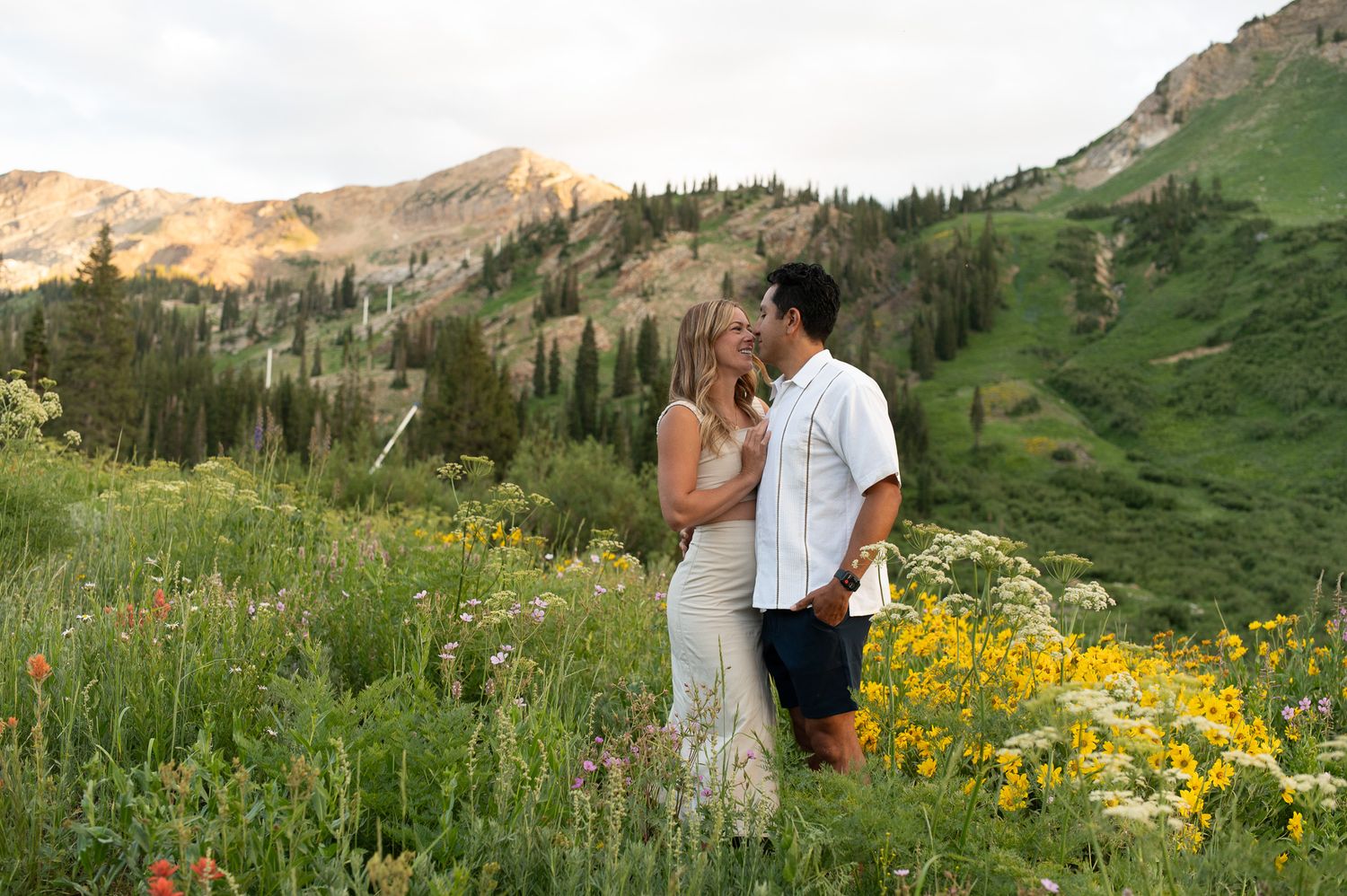 Newlyweds pose together in a stunning mountain meadow filled with vibrant wildflowers.