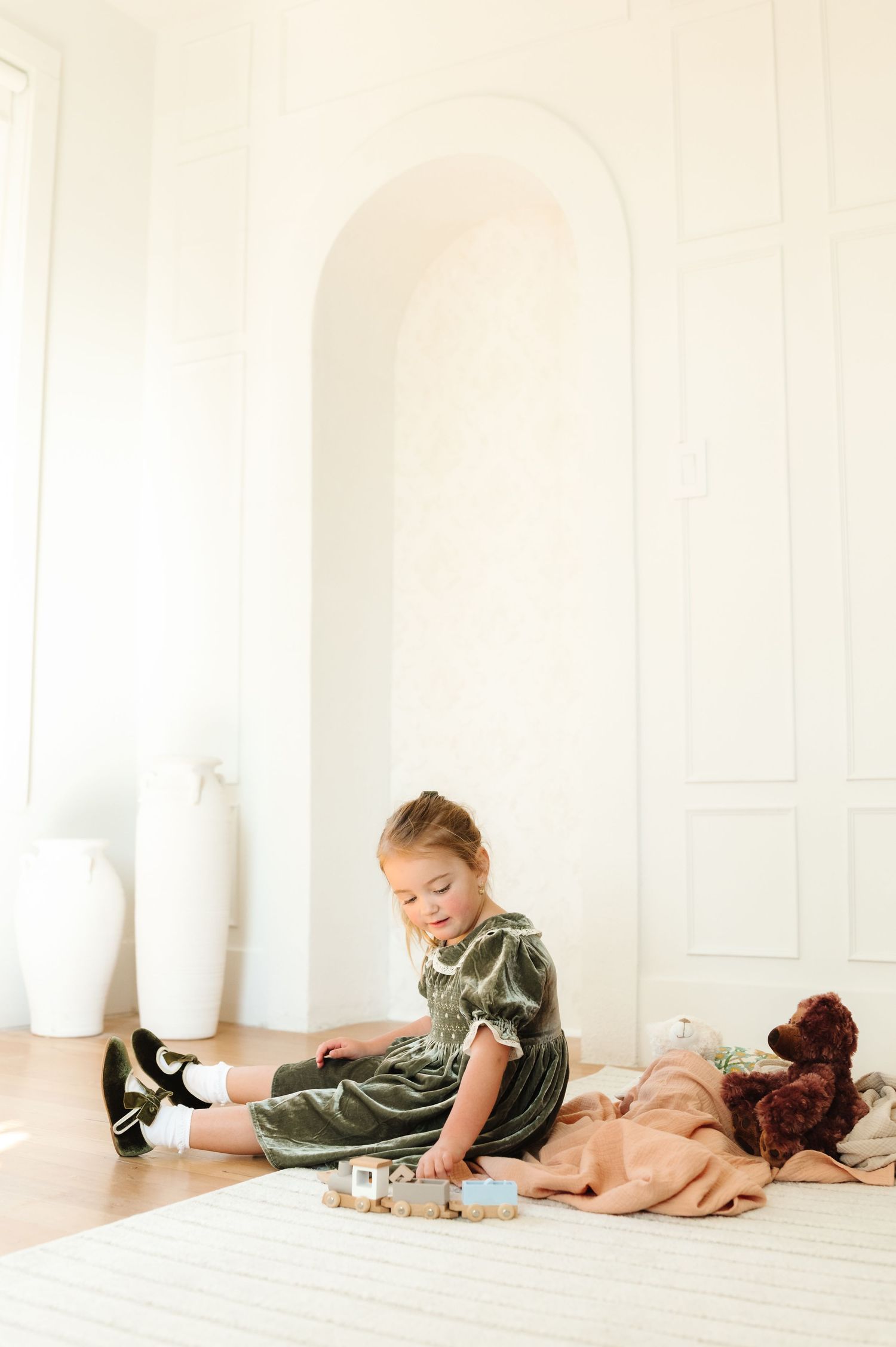 Person relaxing on white floor with stuffed animals and toys.