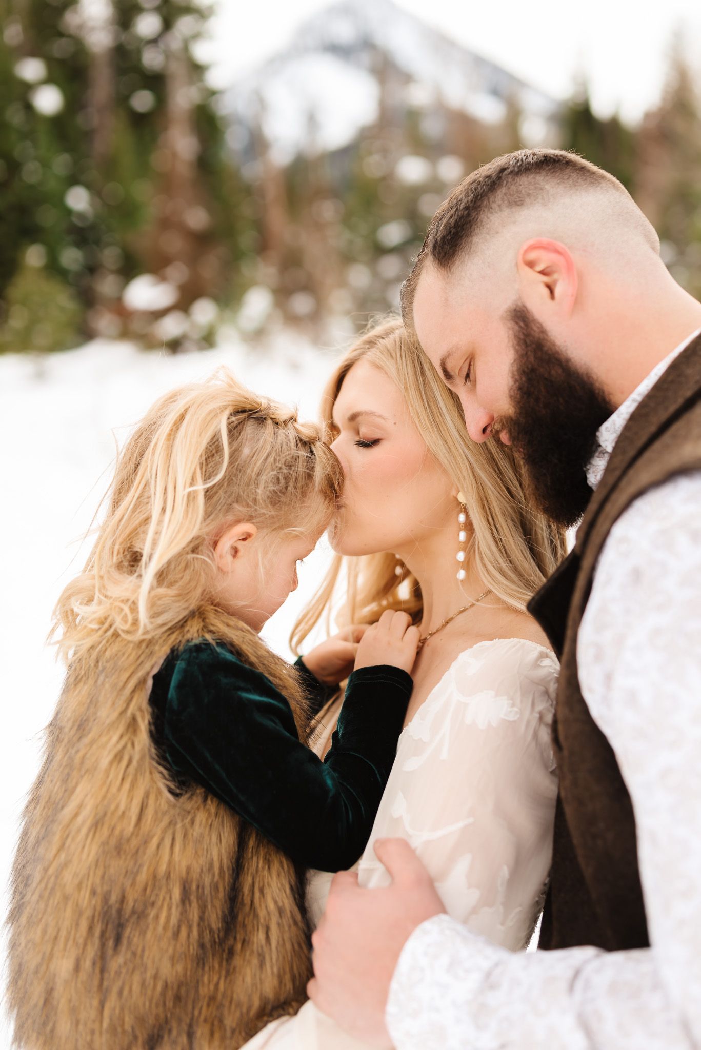Romantic winter engagement photos showing intimate close-up moments against a snowy mountain backdrop.