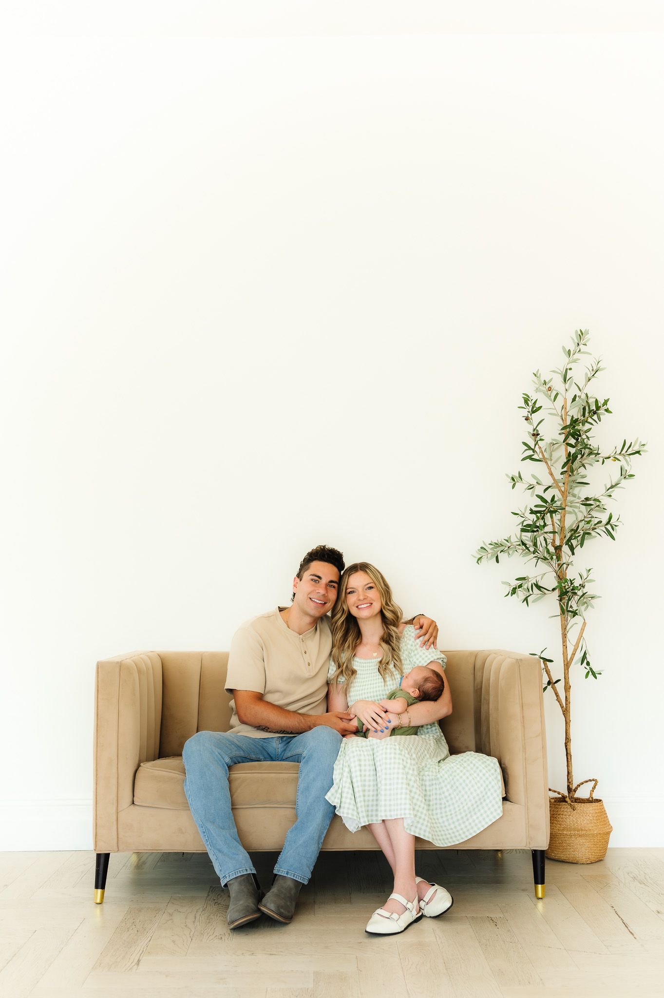 Minimalist indoor portrait on beige couch with decorative plant in corner.