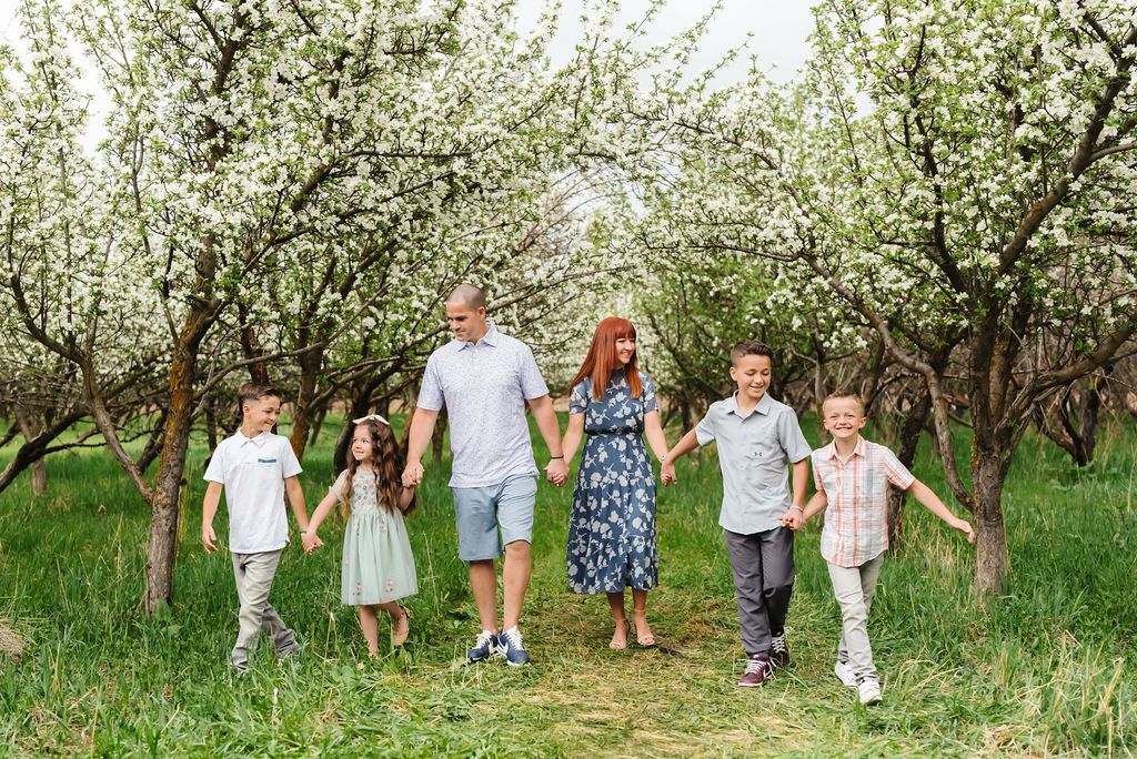 A group walks together through a blooming apple orchard on a spring day.