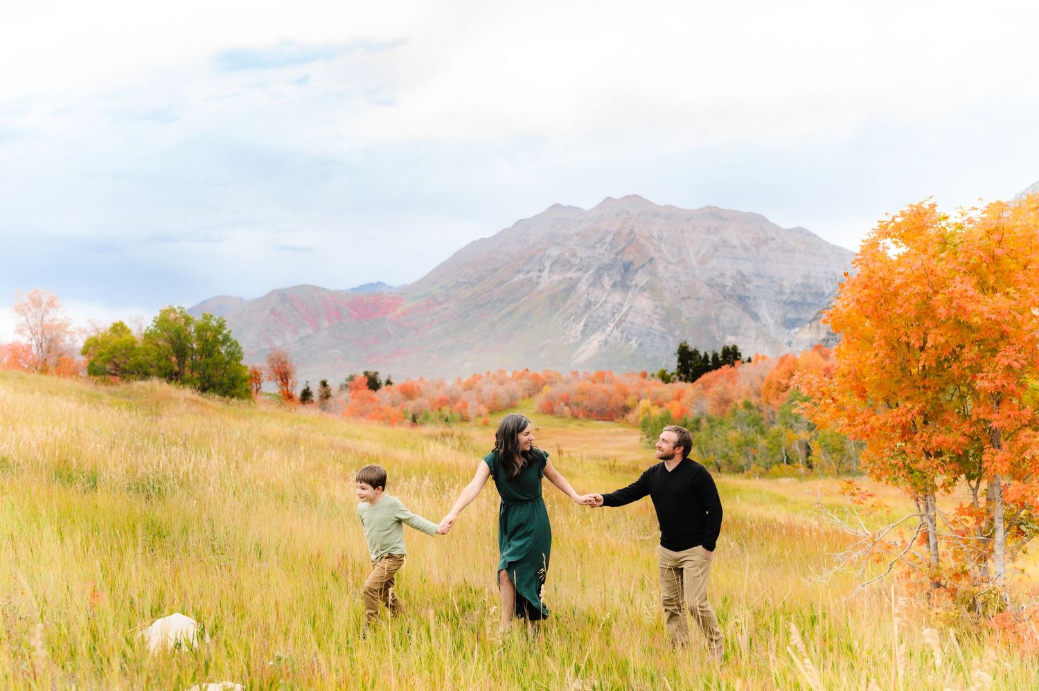 People walking and posing together in a mountain meadow during sunset.