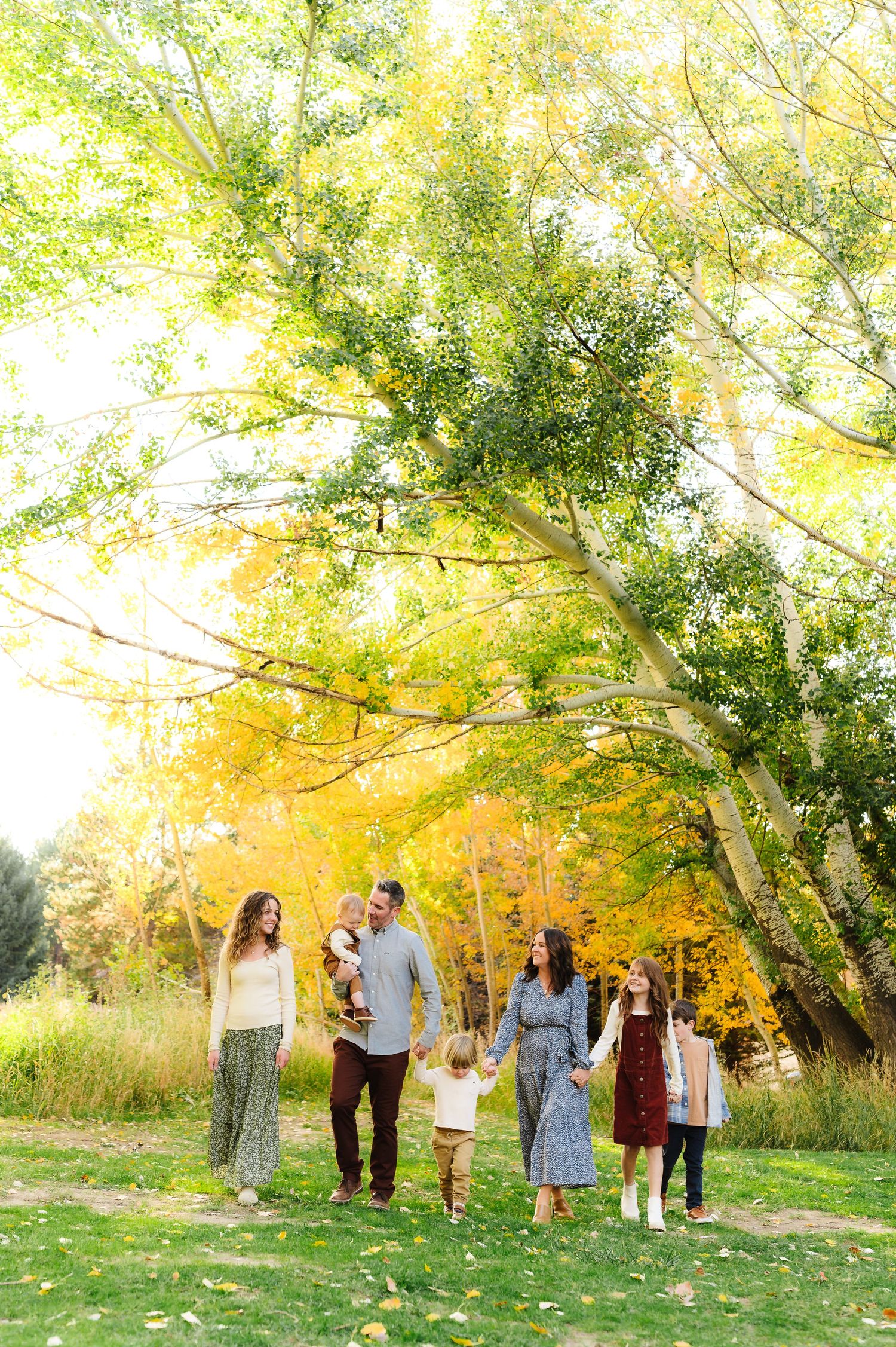 Family group poses together in a scenic wooded area with stunning fall colors.