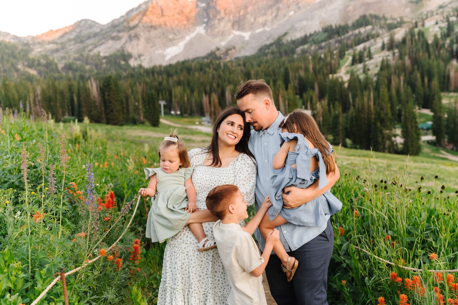 Sunset family photography in a mountain meadow with golden light on rocky peaks.