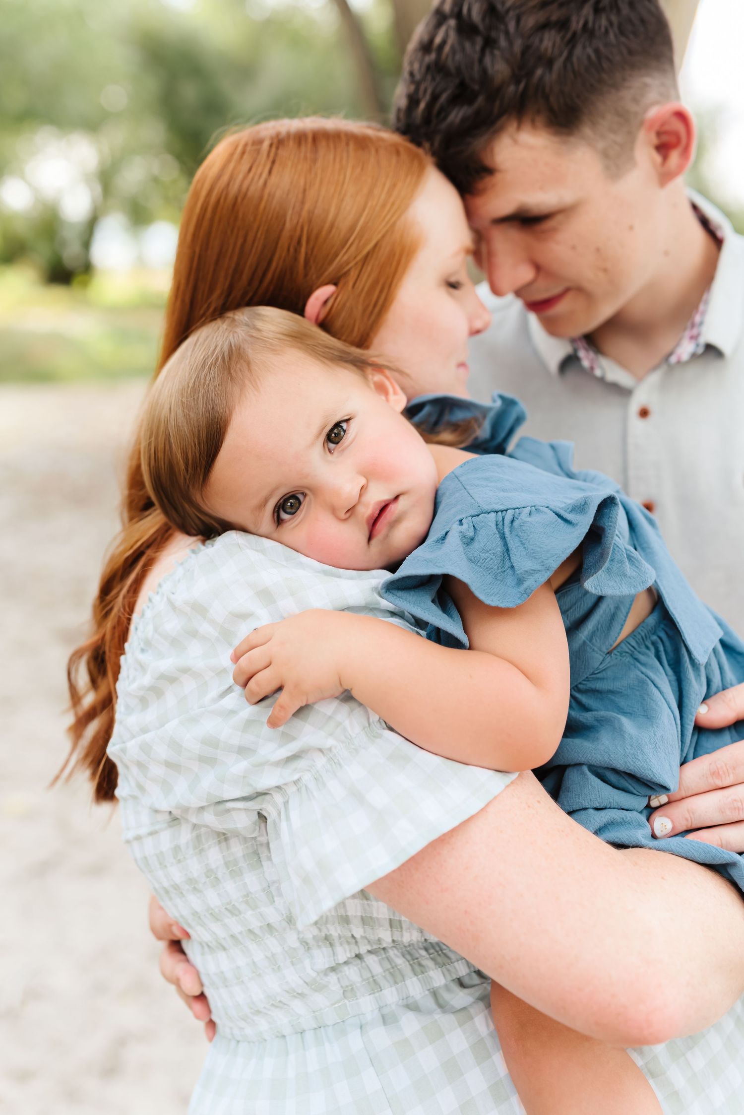 Tender family moment captured in soft natural light wearing blue and white outfits.