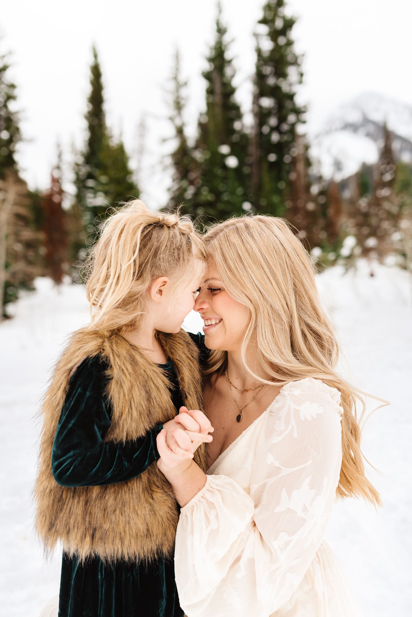 Joyful winter family photography session with snow-covered mountains in the distance.