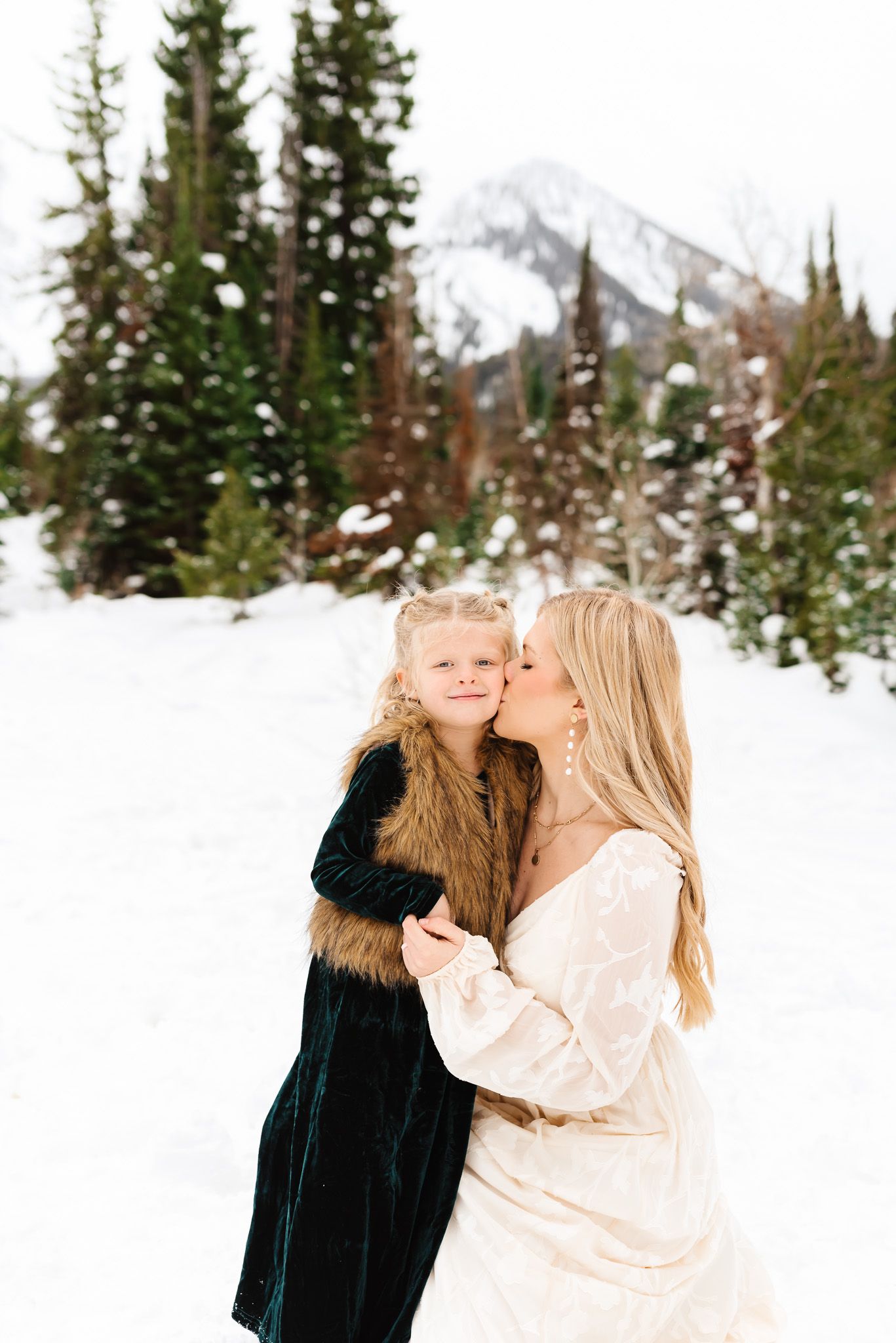 Tender family moments photographed in sequence against a wintry mountain landscape during winter family photos at Jordan Pines