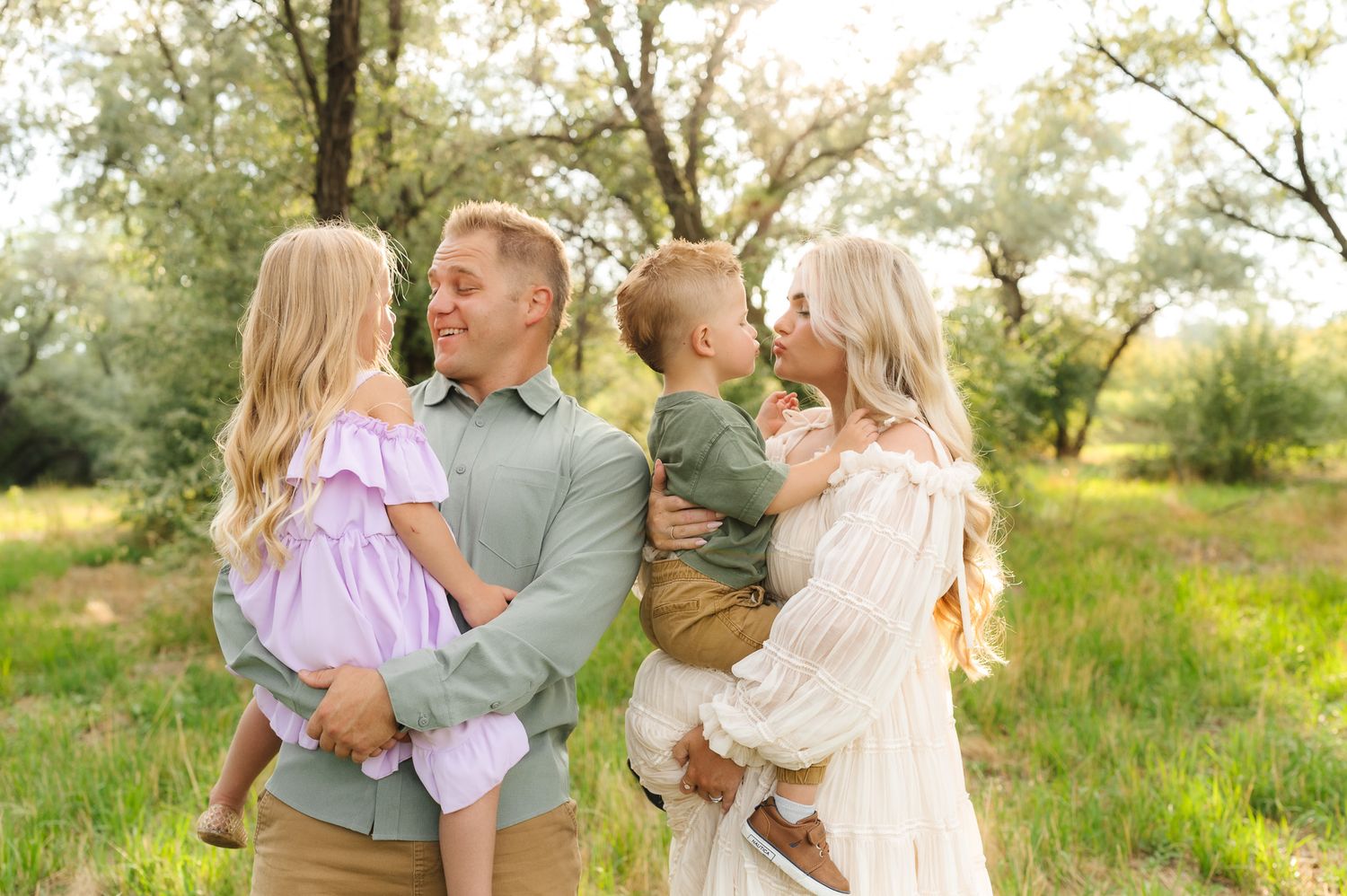 Family photo session in a grassy field during golden hour.