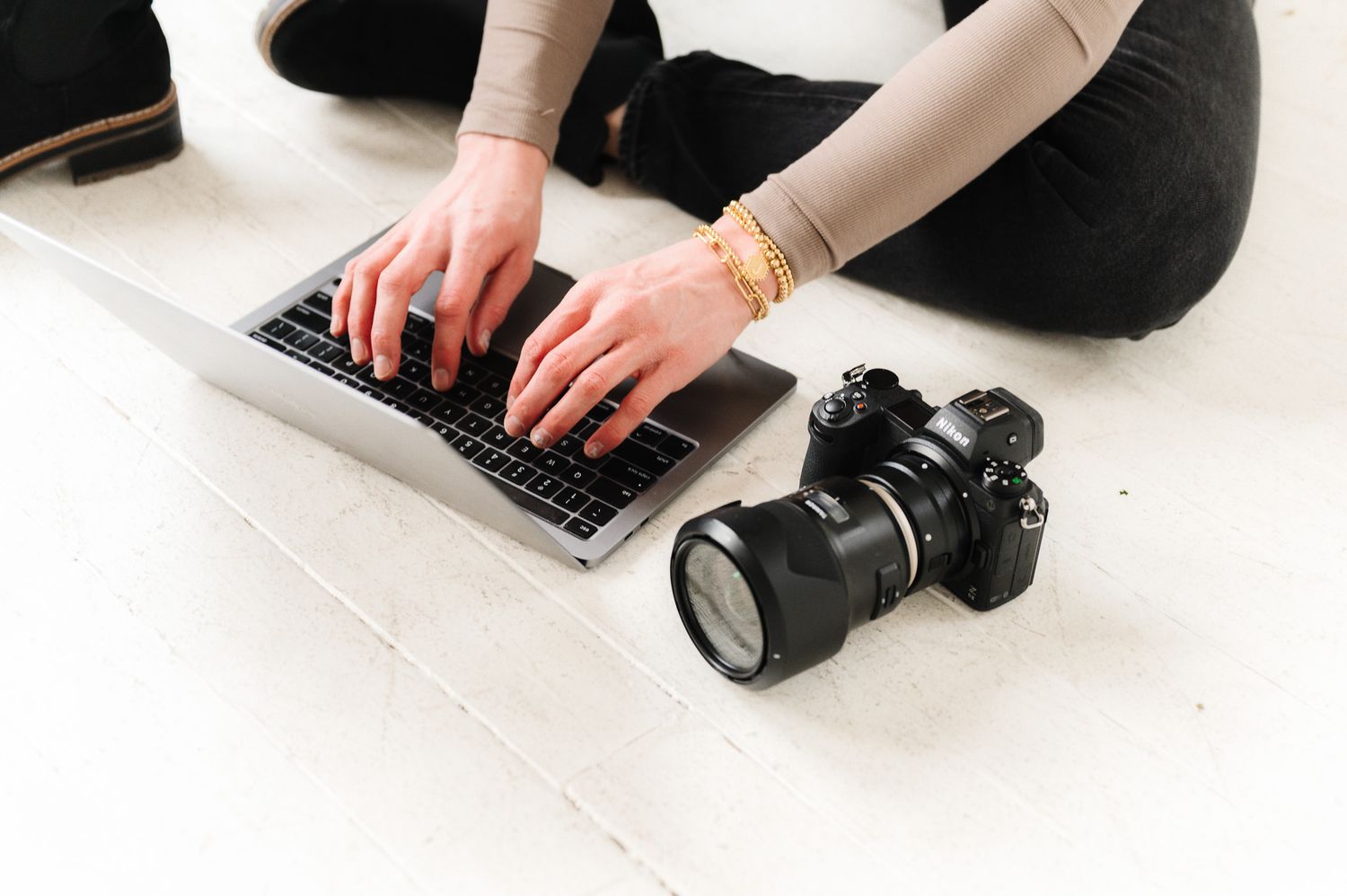 Close-up of hands typing on laptop keyboard with professional camera nearby.