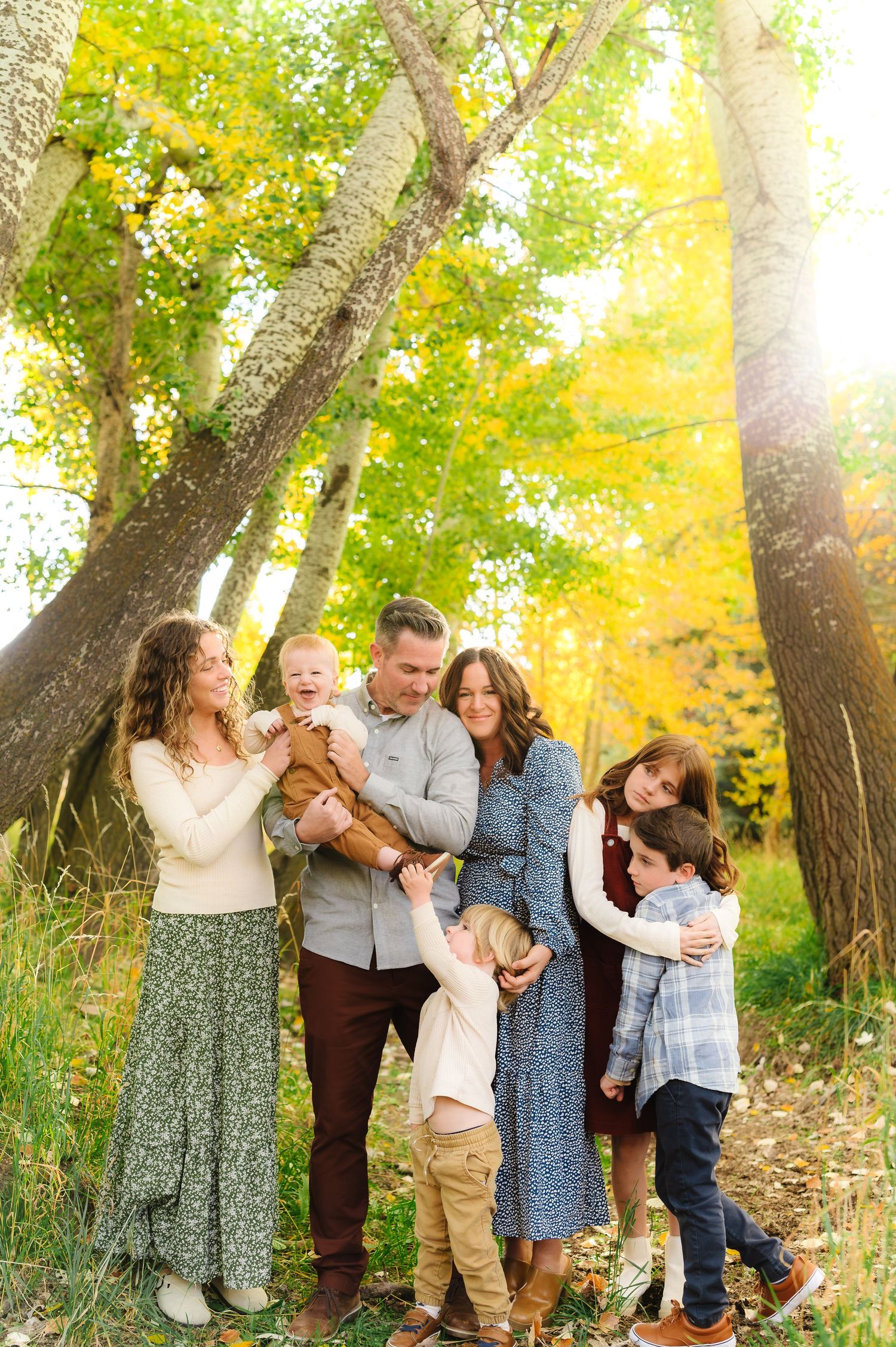 Group portrait session in a sunlit autumn forest with golden leaves.