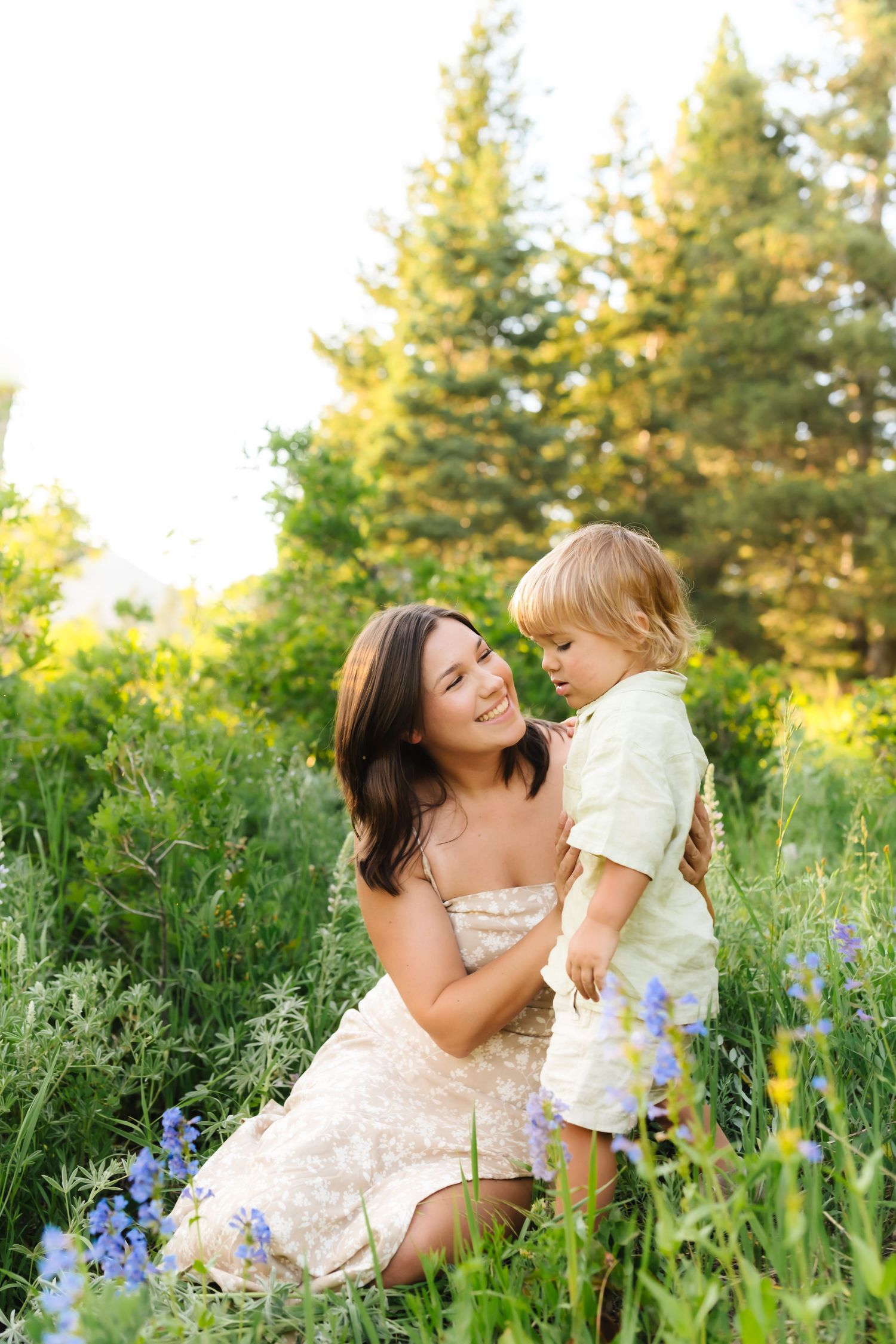 A tender moment between parent and child sitting among vibrant wildflowers in a sunlit meadow.