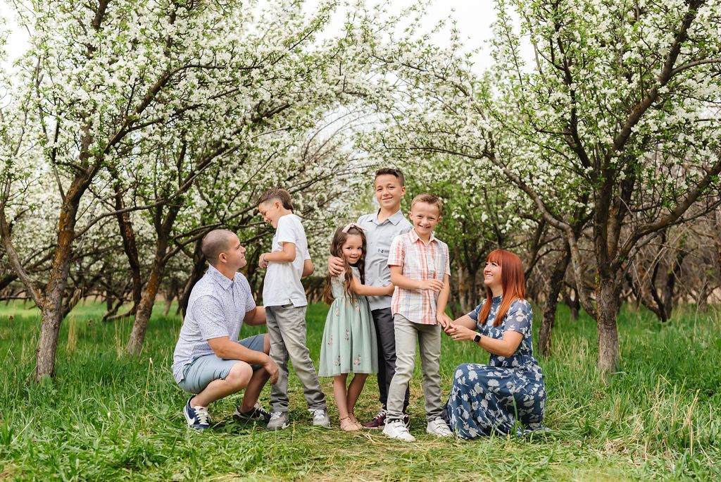 A casual family gathering captured among flowering trees in a spring orchard setting.