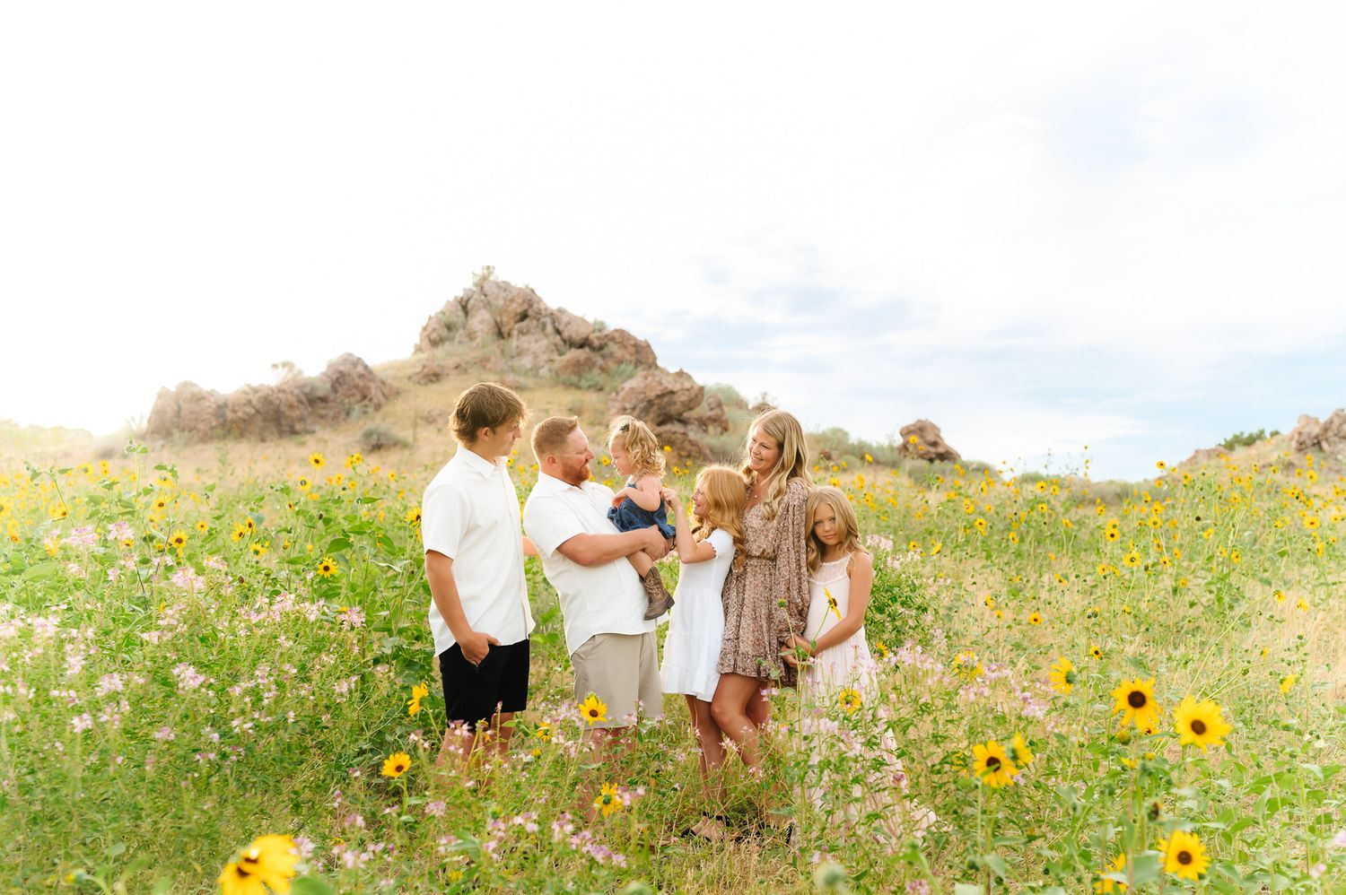 Family photo session in a field of blooming sunflowers on a bright summer day.