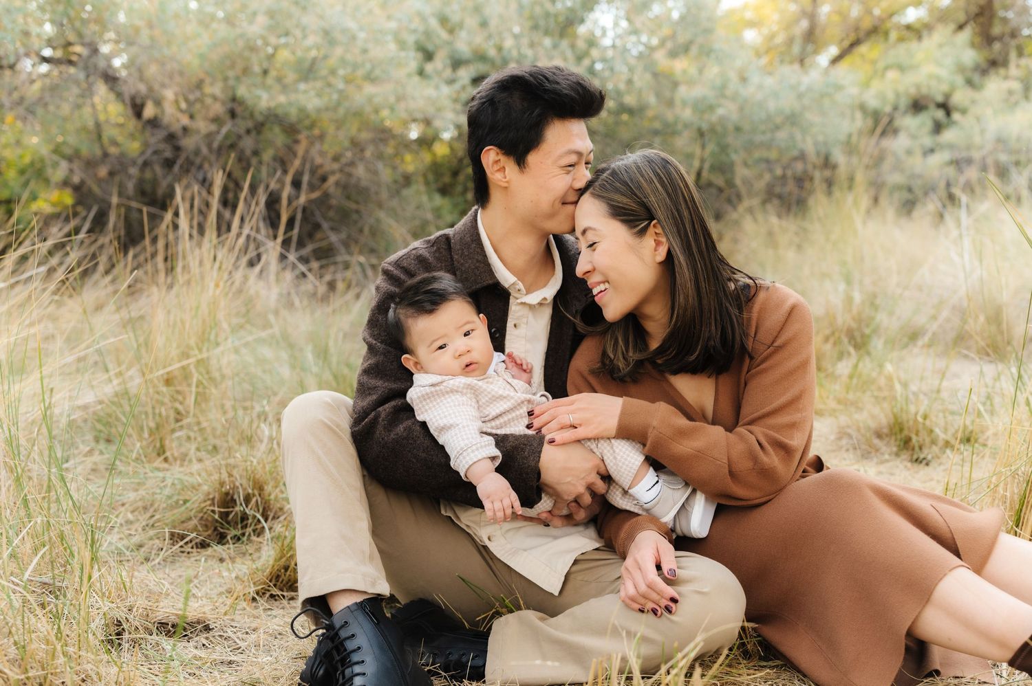 Couple sharing intimate moments together in a rustic outdoor setting with golden grass and natural lighting.
