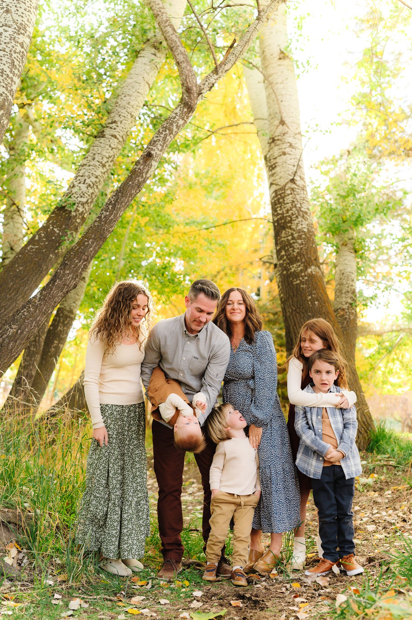 A group stands together under tall trees with golden autumn leaves in the background.