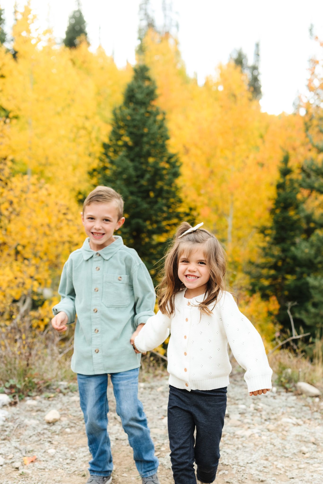 Children running and playing together on a mountain trail surrounded by golden fall foliage.
