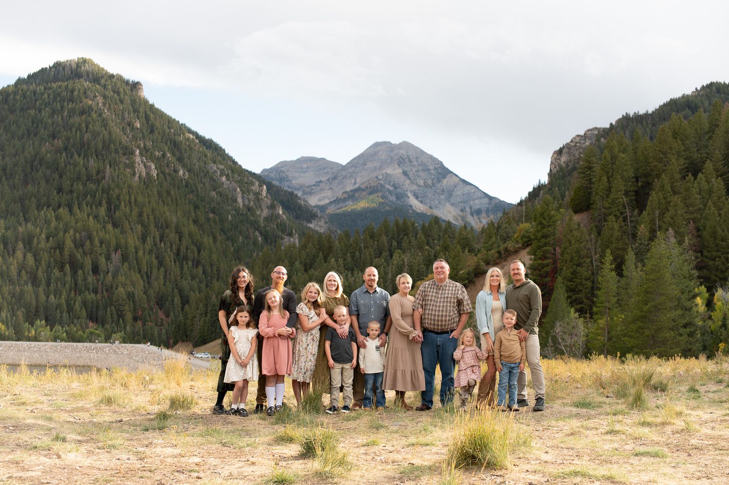 Extended family group portrait standing in a mountain valley surrounded by pine trees and rocky peaks.