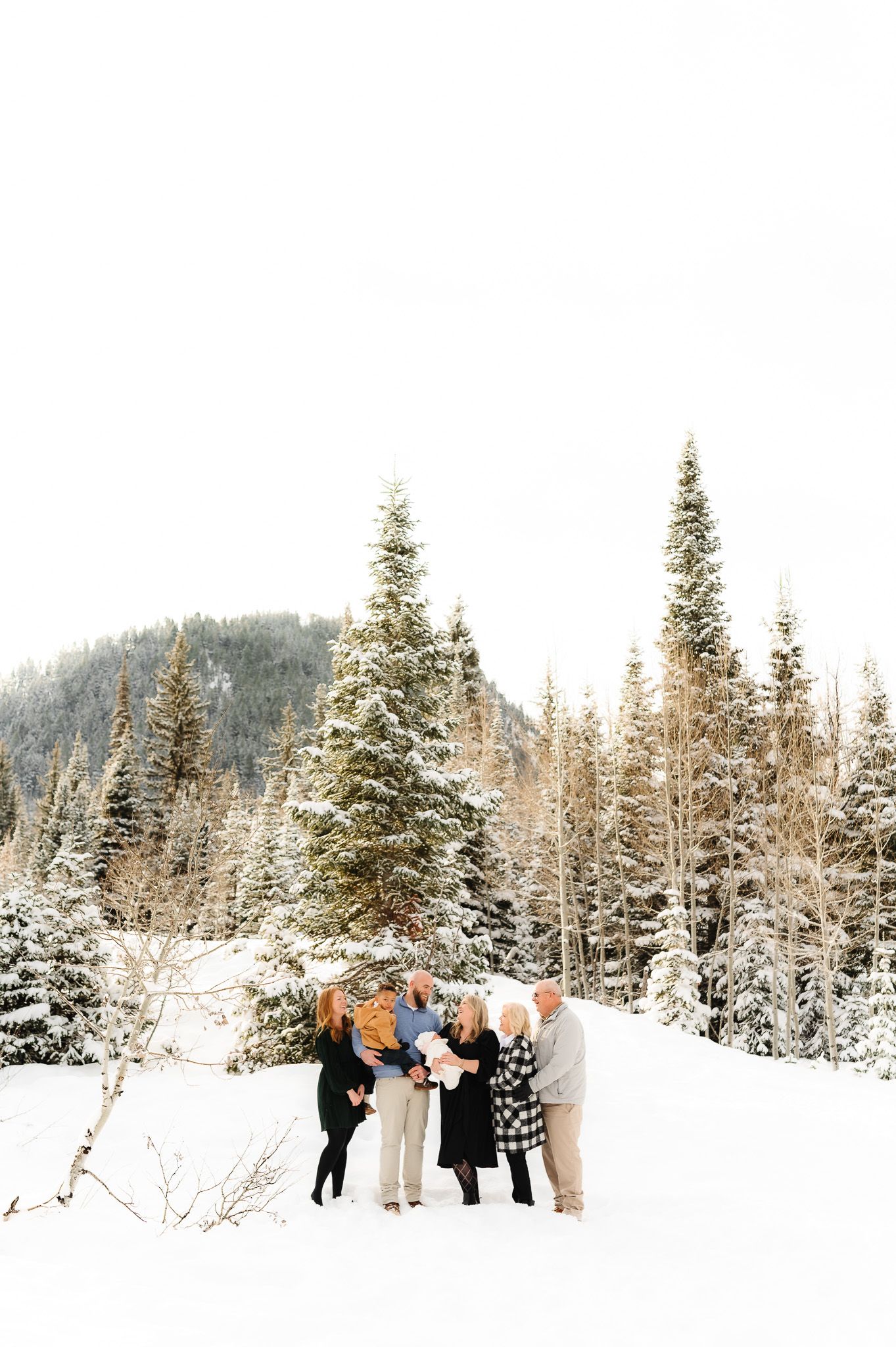 Winter group photo with snow-covered pine trees in a mountain setting.