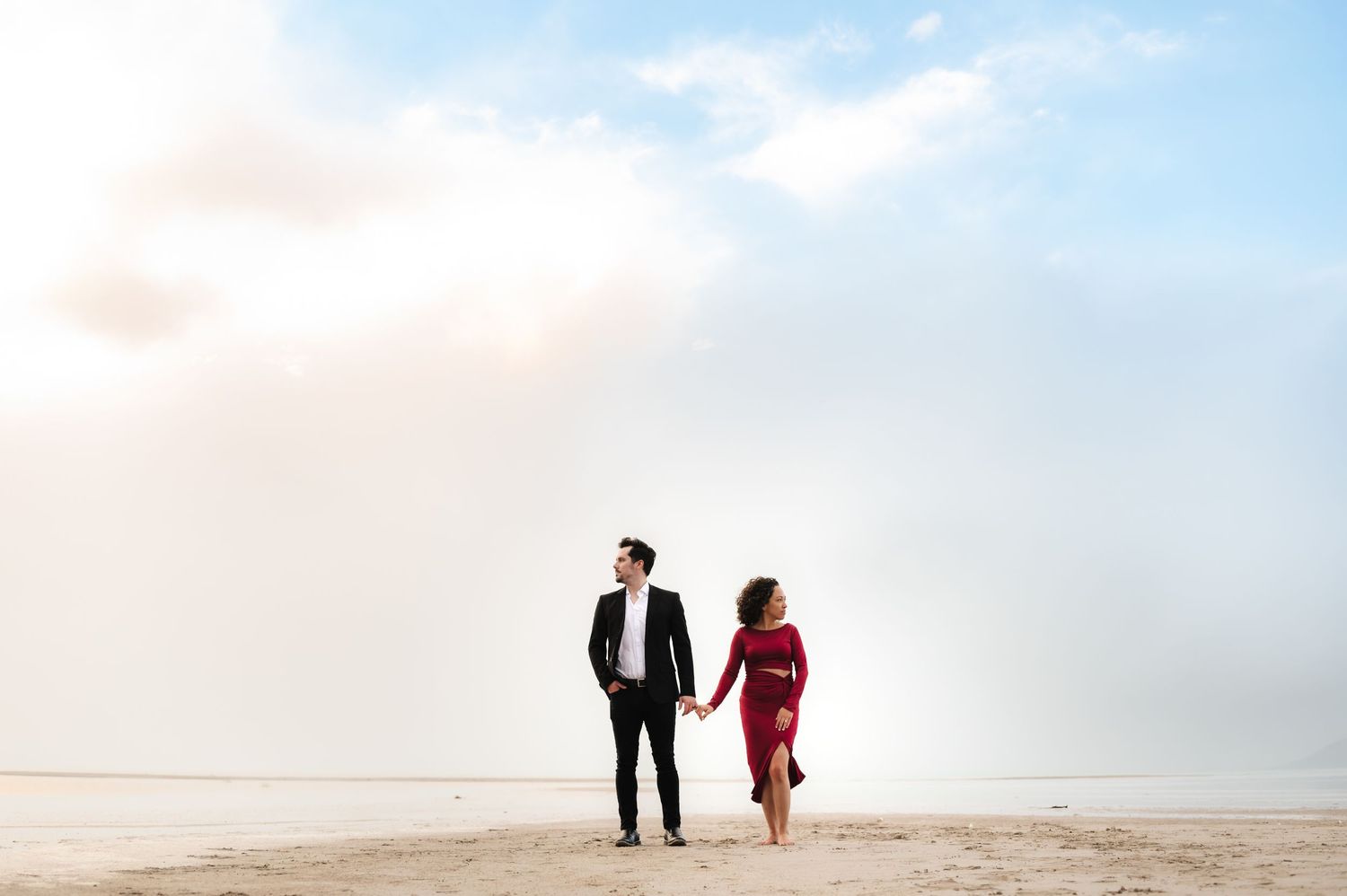 Couple walking together on a scenic beach at sunset with soft lighting and sandy shores.