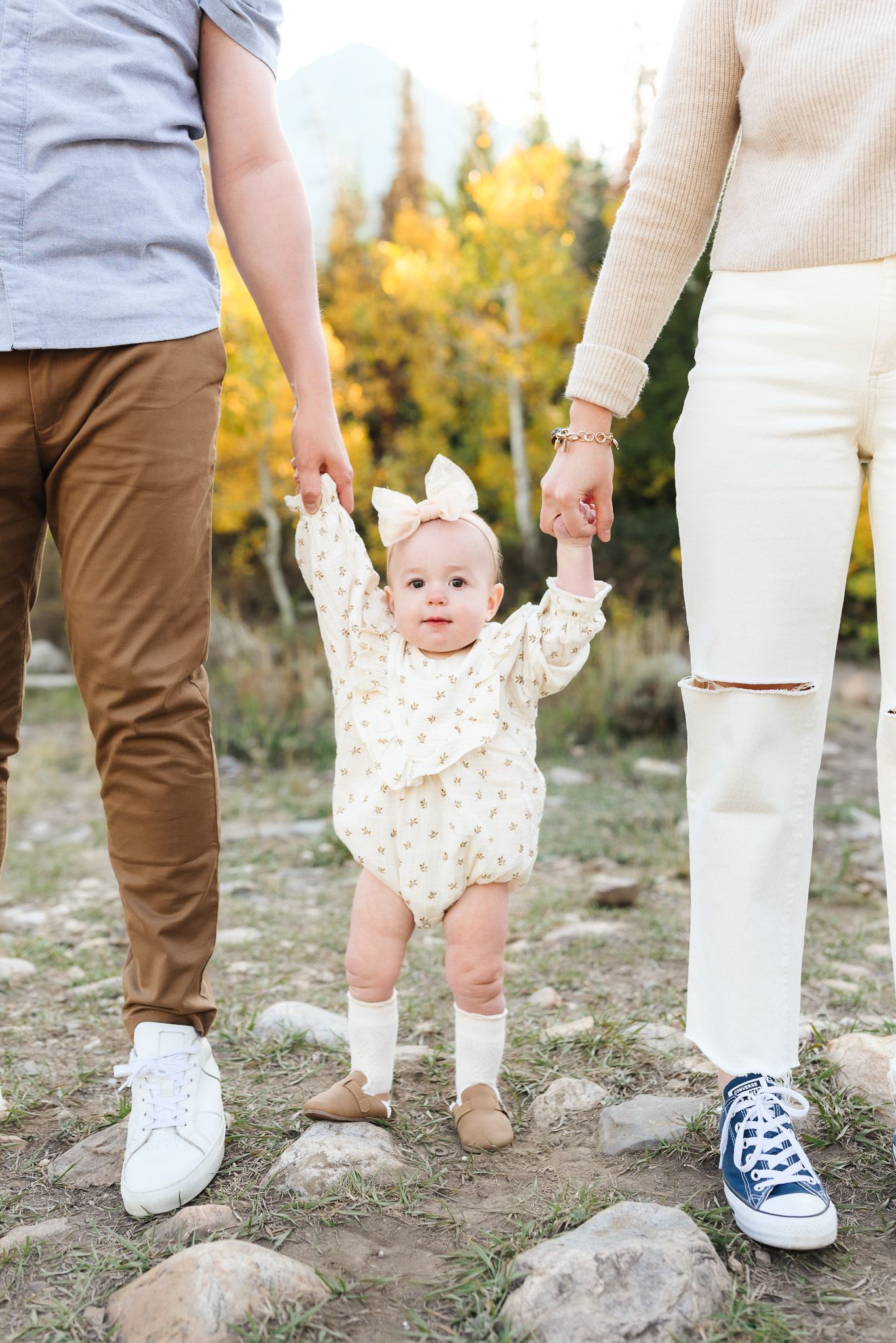 Close-up of family members' feet and legs standing together on rocky mountain terrain.