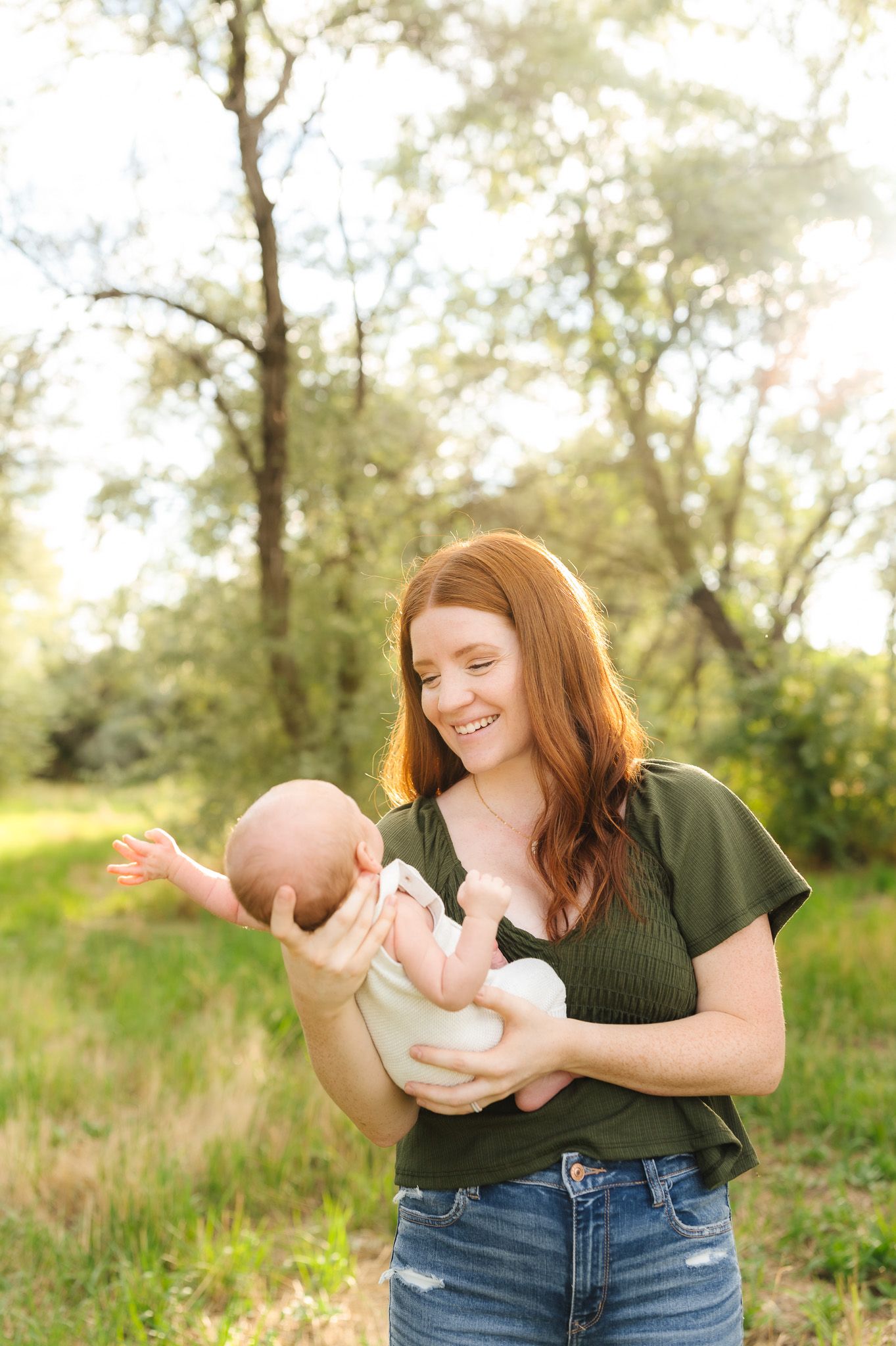 Playful outdoor photoshoot with baby in a natural setting with golden sunlight.
