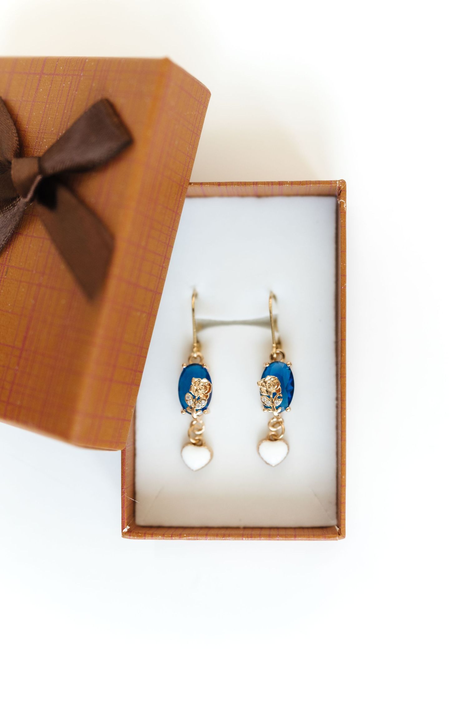 Pearl and blue enamel earrings presented in elegant gift boxes with brown bows.