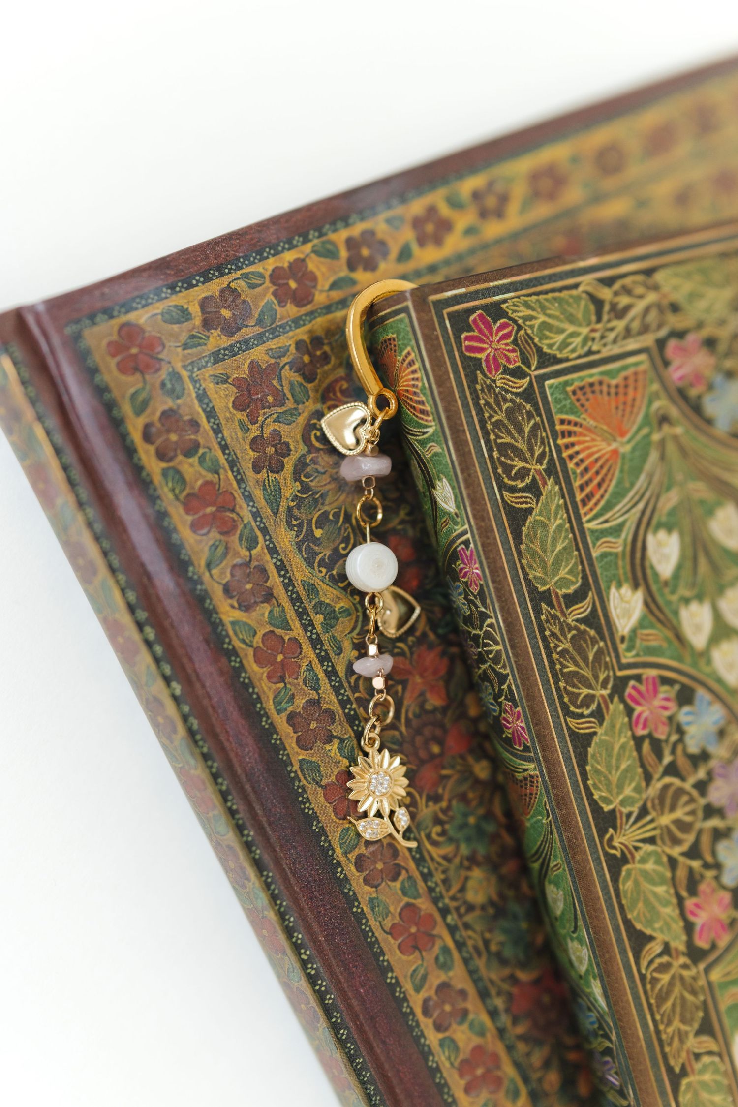 Vintage book with ornate floral pattern and decorative charms attached to the spine.