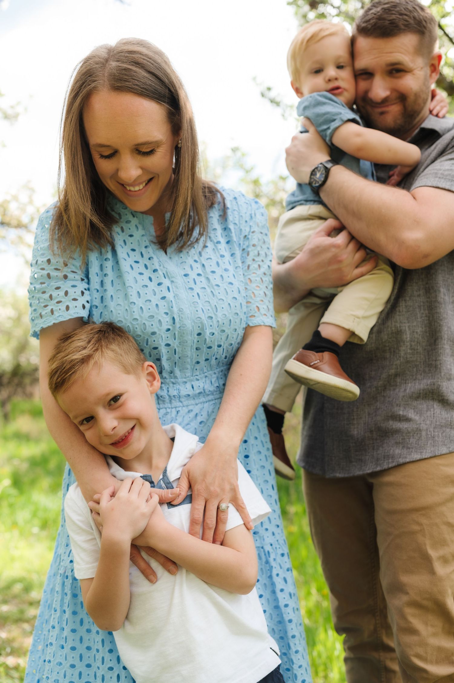 A family shares joyful moments together outdoors in spring, wearing coordinated blue and grey outfits.