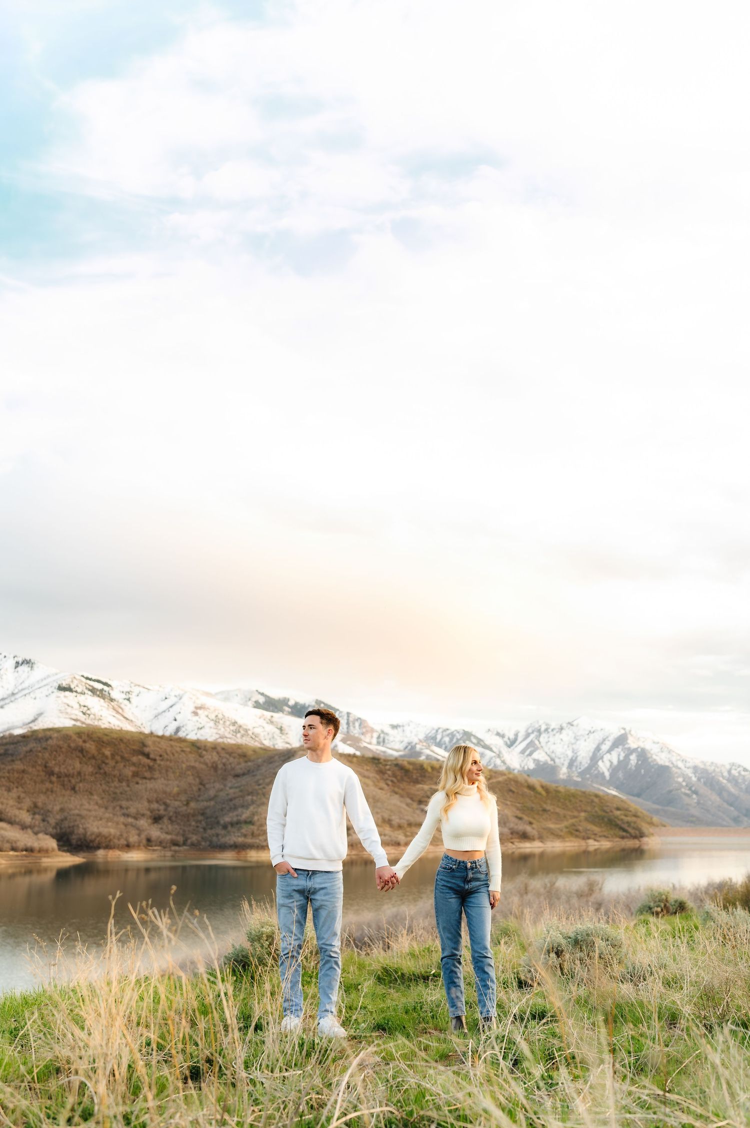 Romantic couple holding hands against mountain landscape with snow-capped peaks.