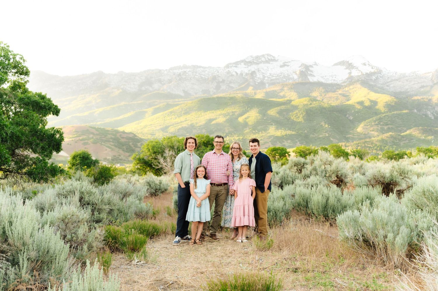 Group portrait in sage brush field with mountain backdrop during golden hour.