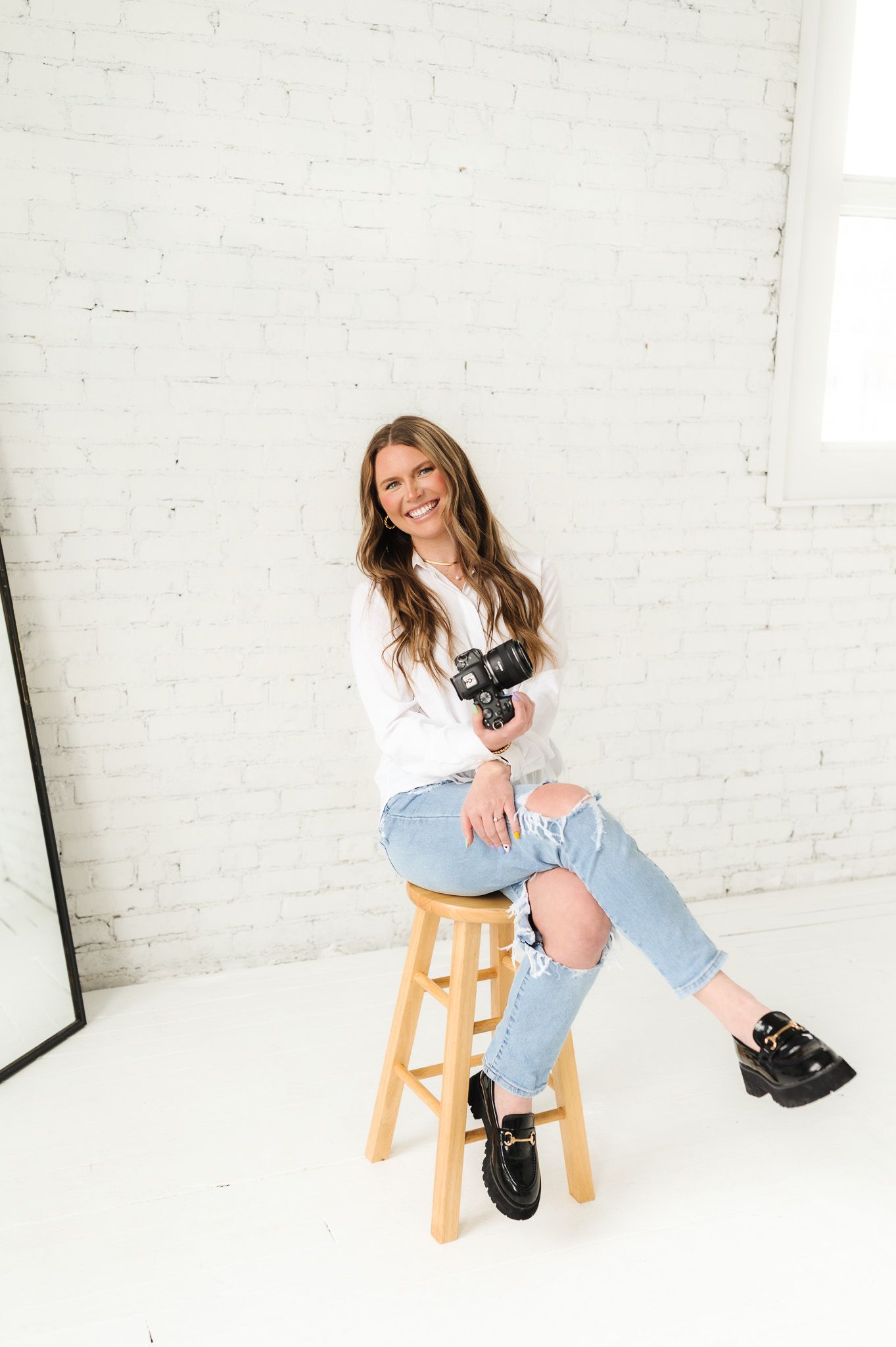 Bright studio portrait with wooden stool and casual fashion styling.