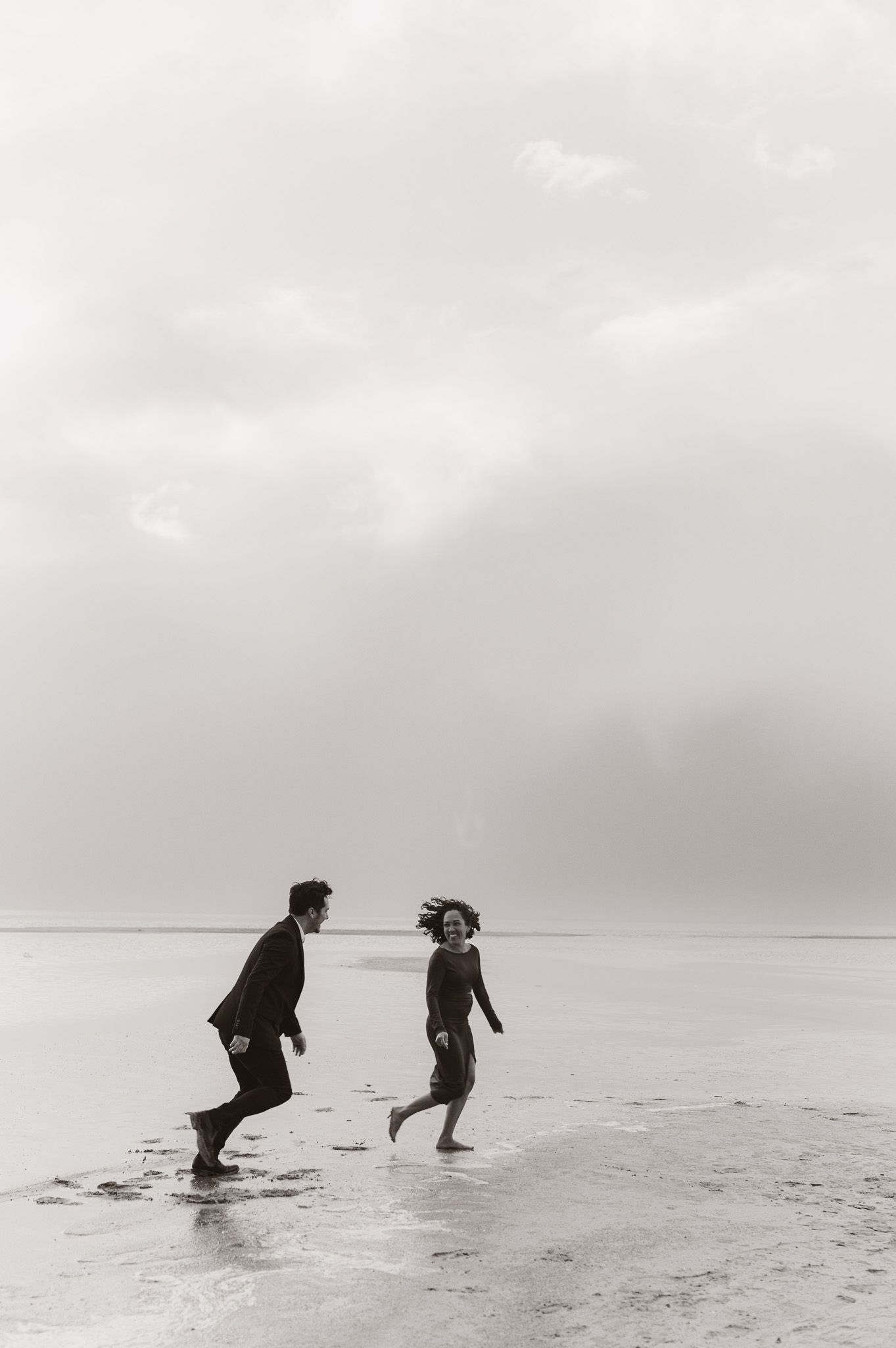 Silhouettes of people playing and running on a misty beach.
