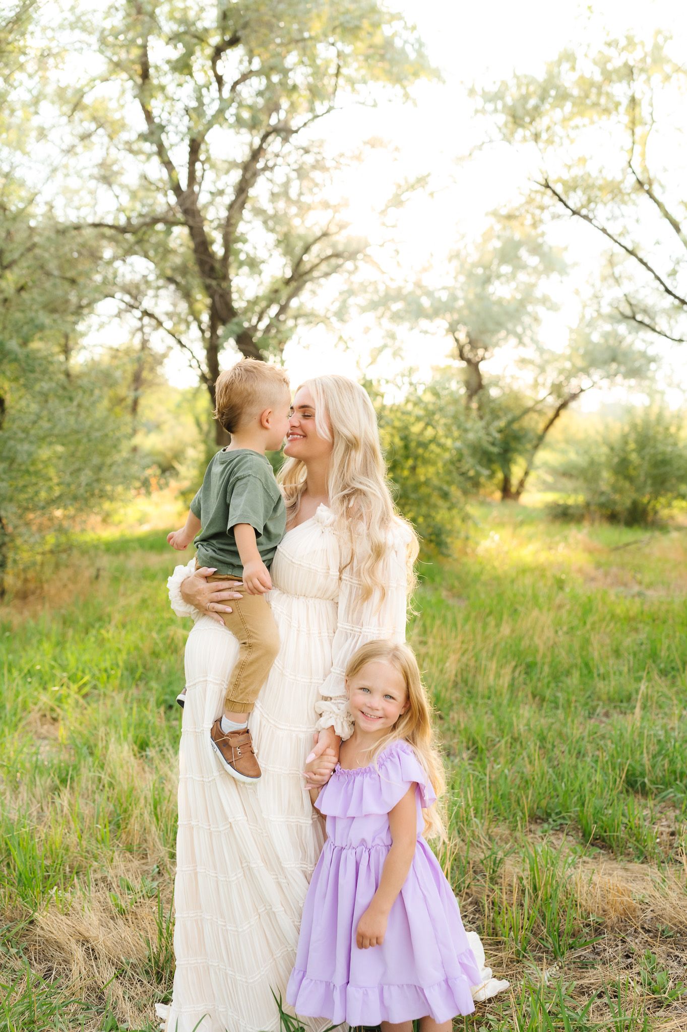 Sweet family moments captured in a sunlit meadow with soft spring colors.
