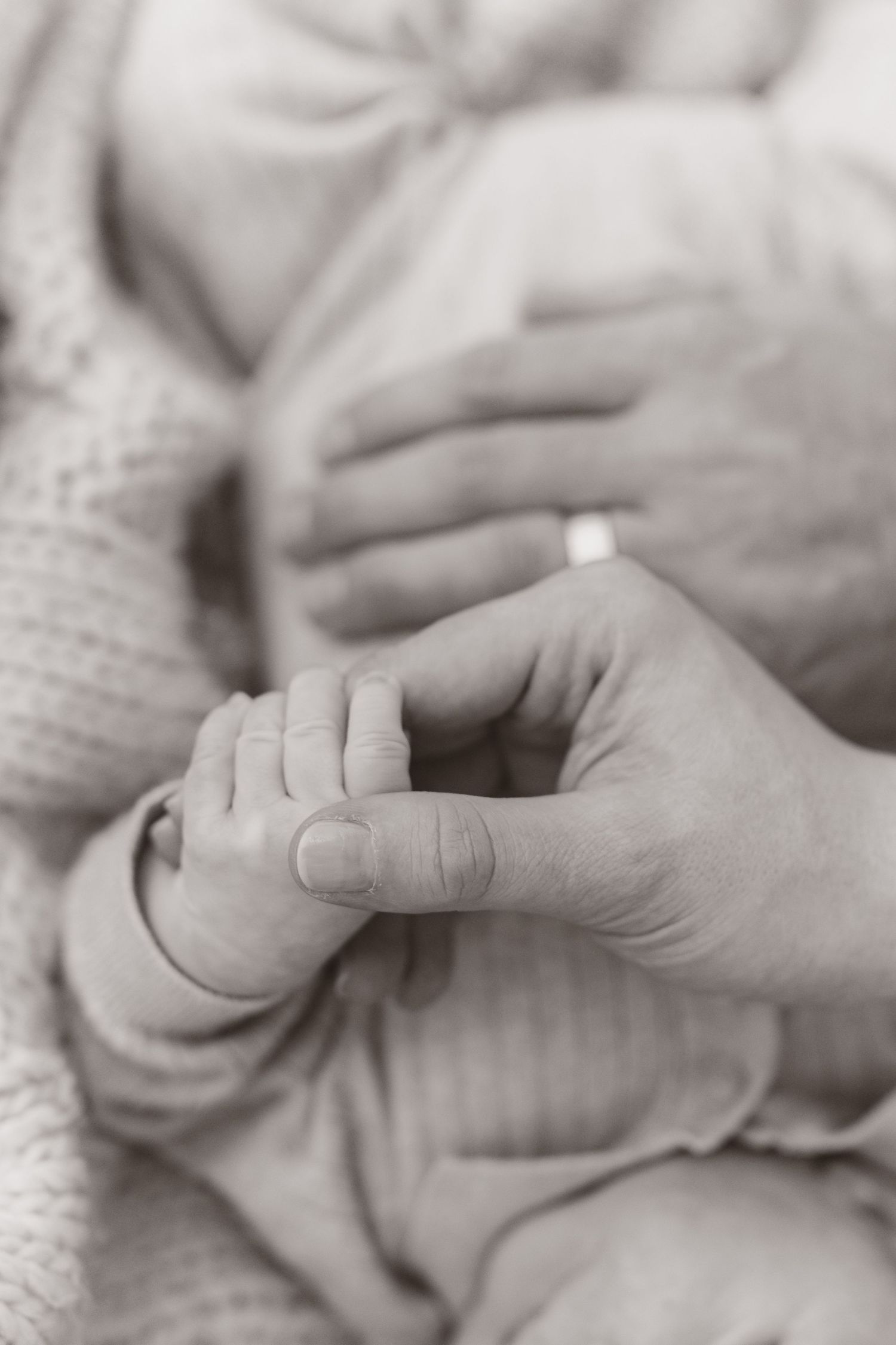 Close-up black and white photo series showing tiny baby fingers grasping an adult's hand.