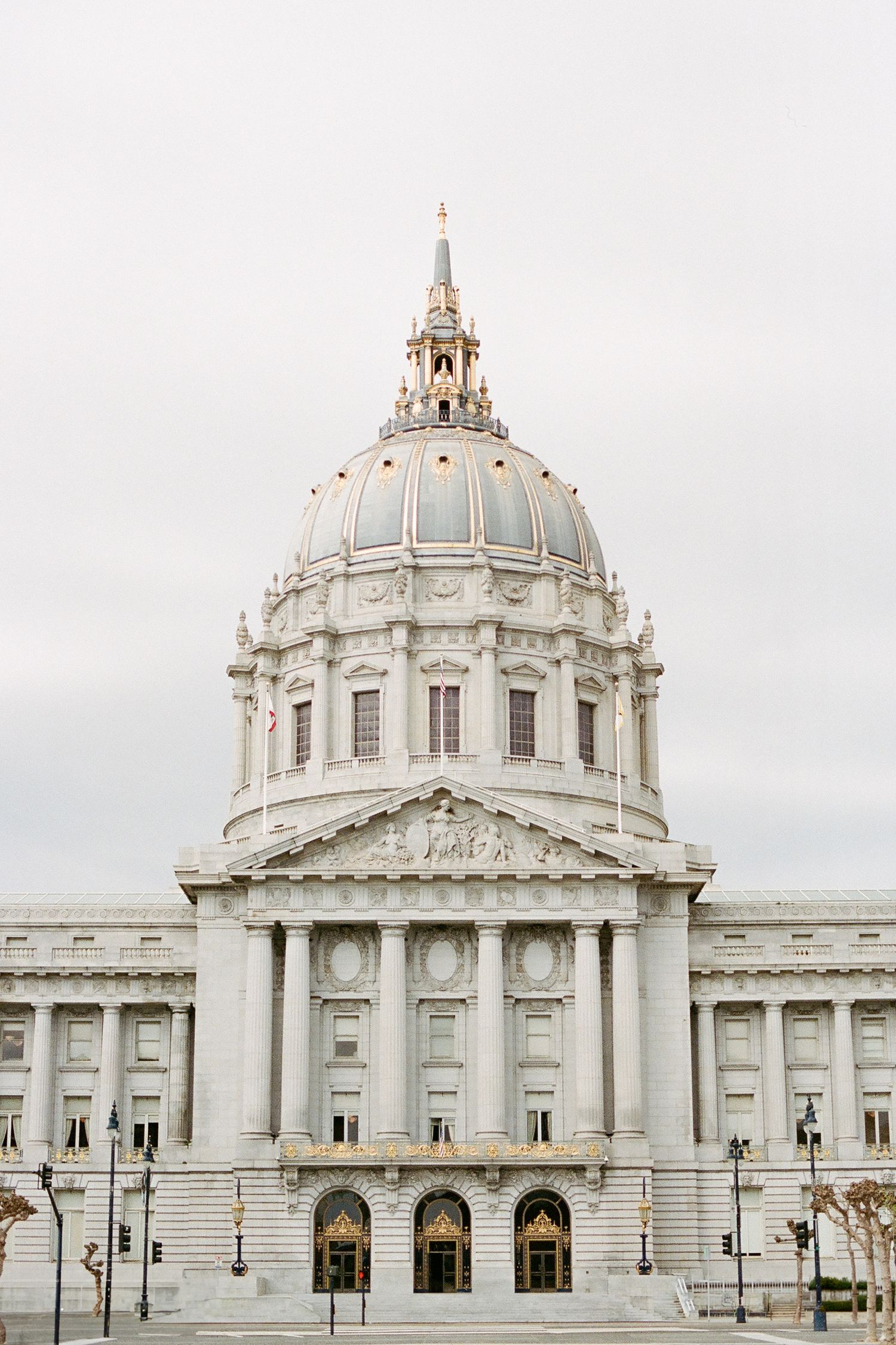 San Francisco City Hall's iconic Beaux-Arts dome and facade photographed against an overcast sky.
