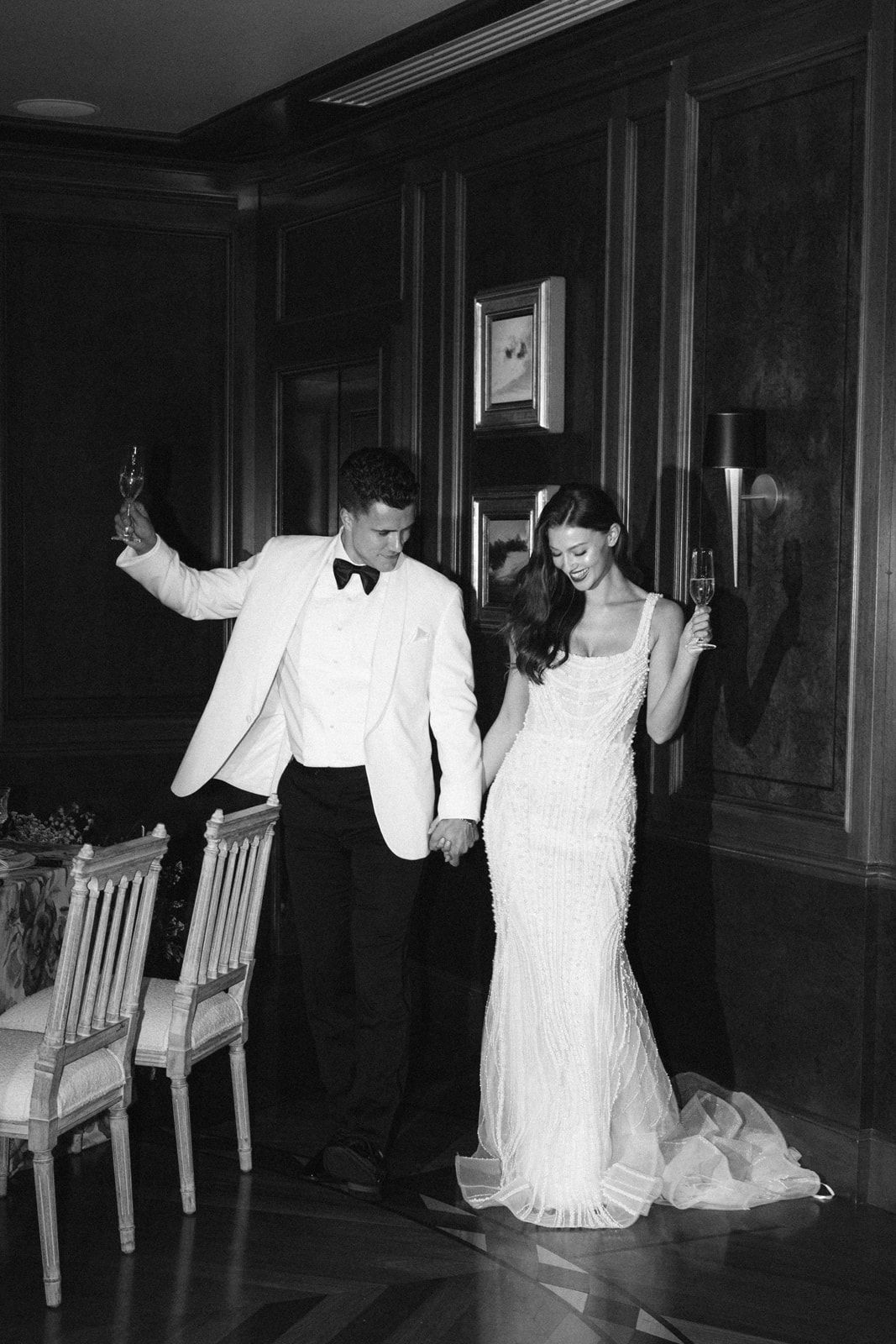A series of four black and white photos showing people in white clothing performing movements in a dimly lit hallway.
