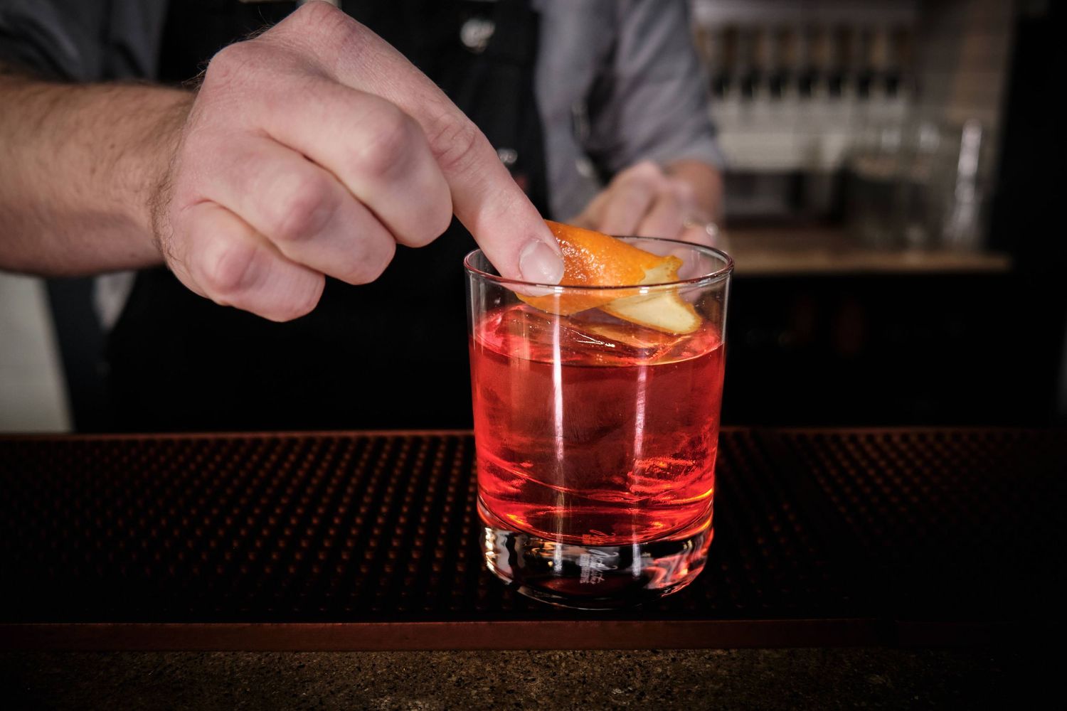Close-up sequence of cocktail preparation showing garnishing of red drinks at a bar.