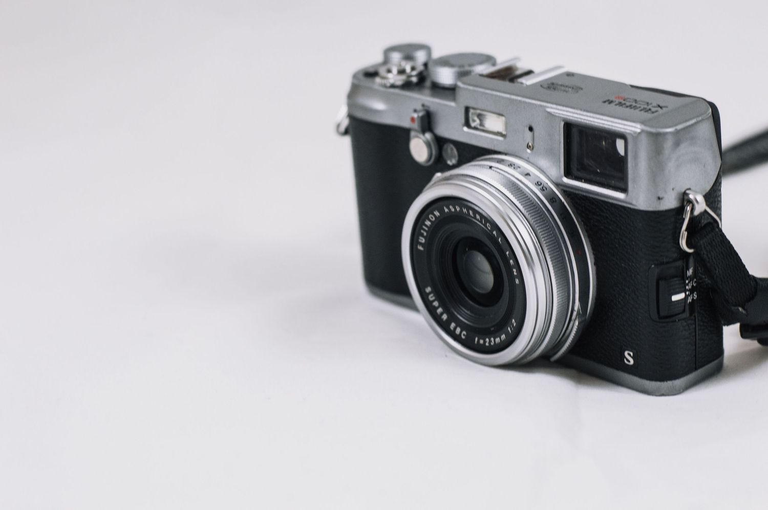 Vintage rangefinder camera on white background with prime lens attached.