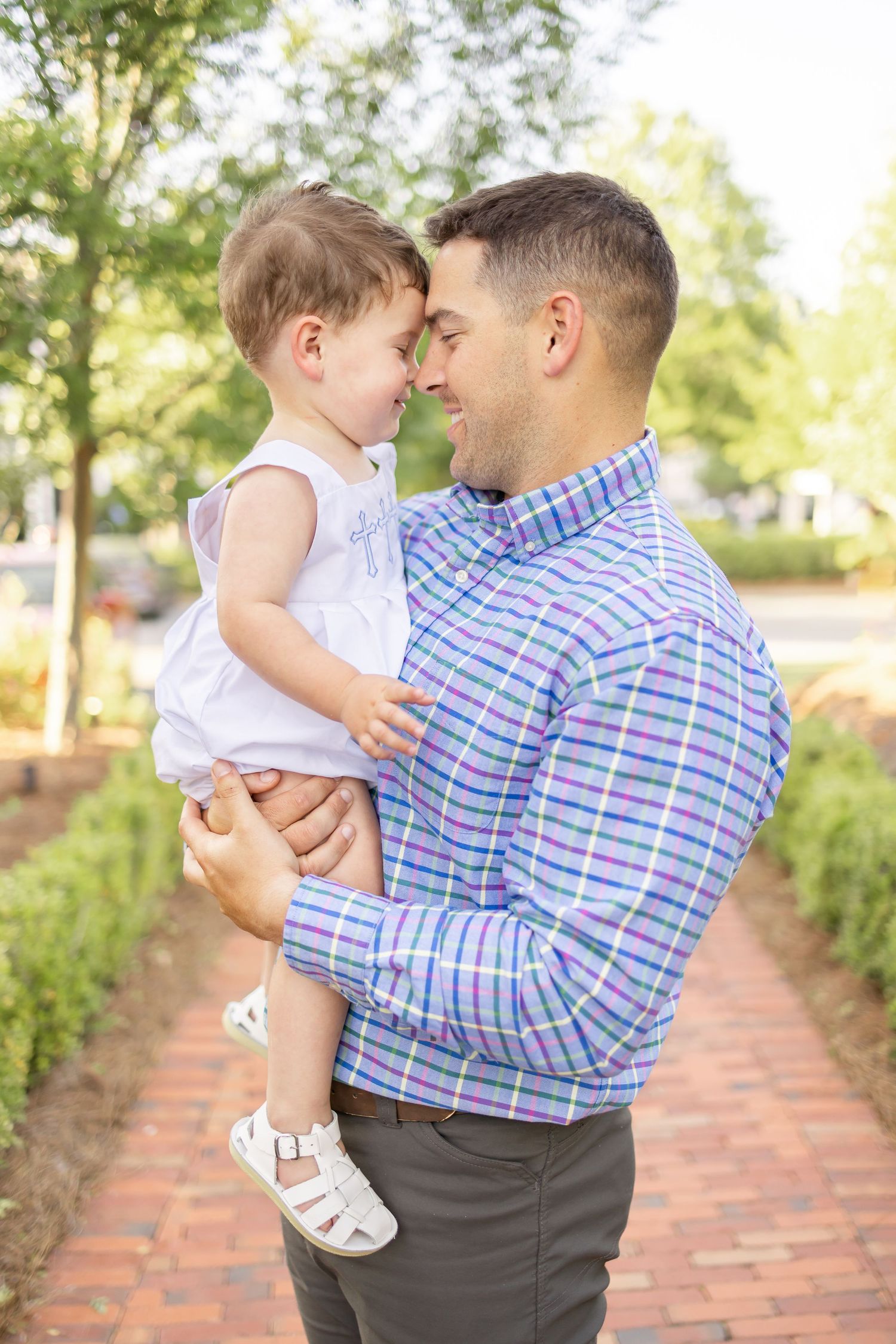 A father in a plaid shirt lovingly holds his son during their spring family portraits in Columbus, GA.