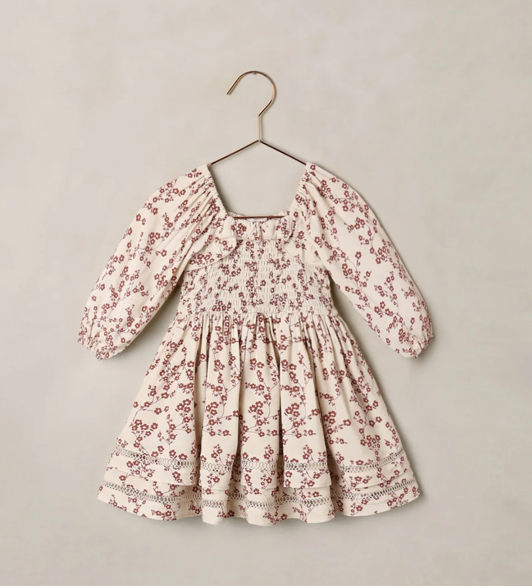 Children's cream floral smocked dress with puff sleeves and tiered skirt on a hanger.