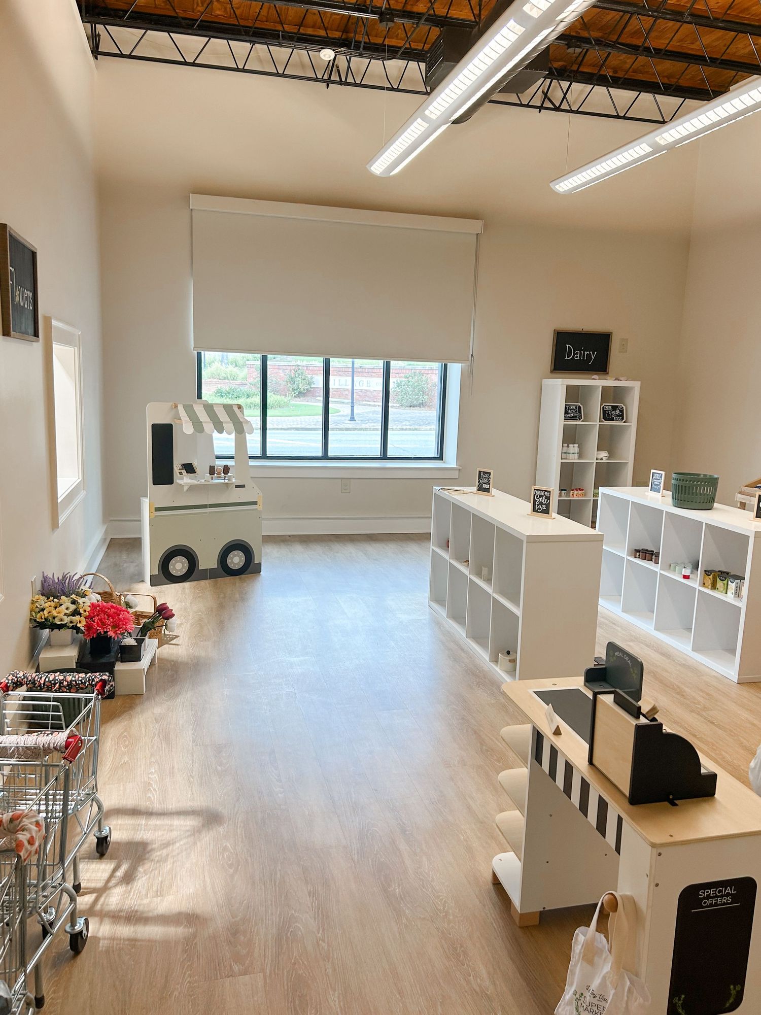 Modern open office space with white walls, wood flooring, and built-in storage shelves showcasing a minimalist design aesthetic.