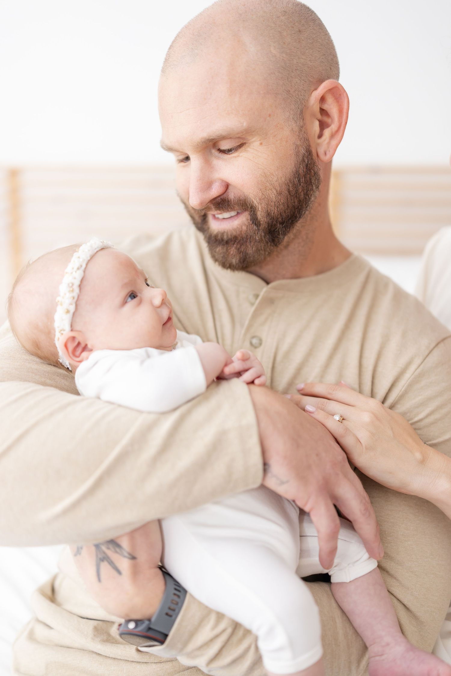A tender moment between a father and his baby girl wearing neutral outfits by newborn photographer Carolina Bowers Photography.