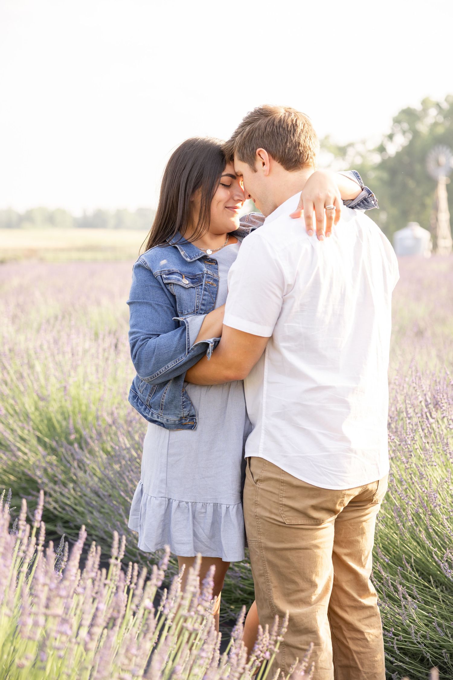 A romantic couple embraces in a blooming lavender field on a sunny afternoon by Columbus, GA family photographer.