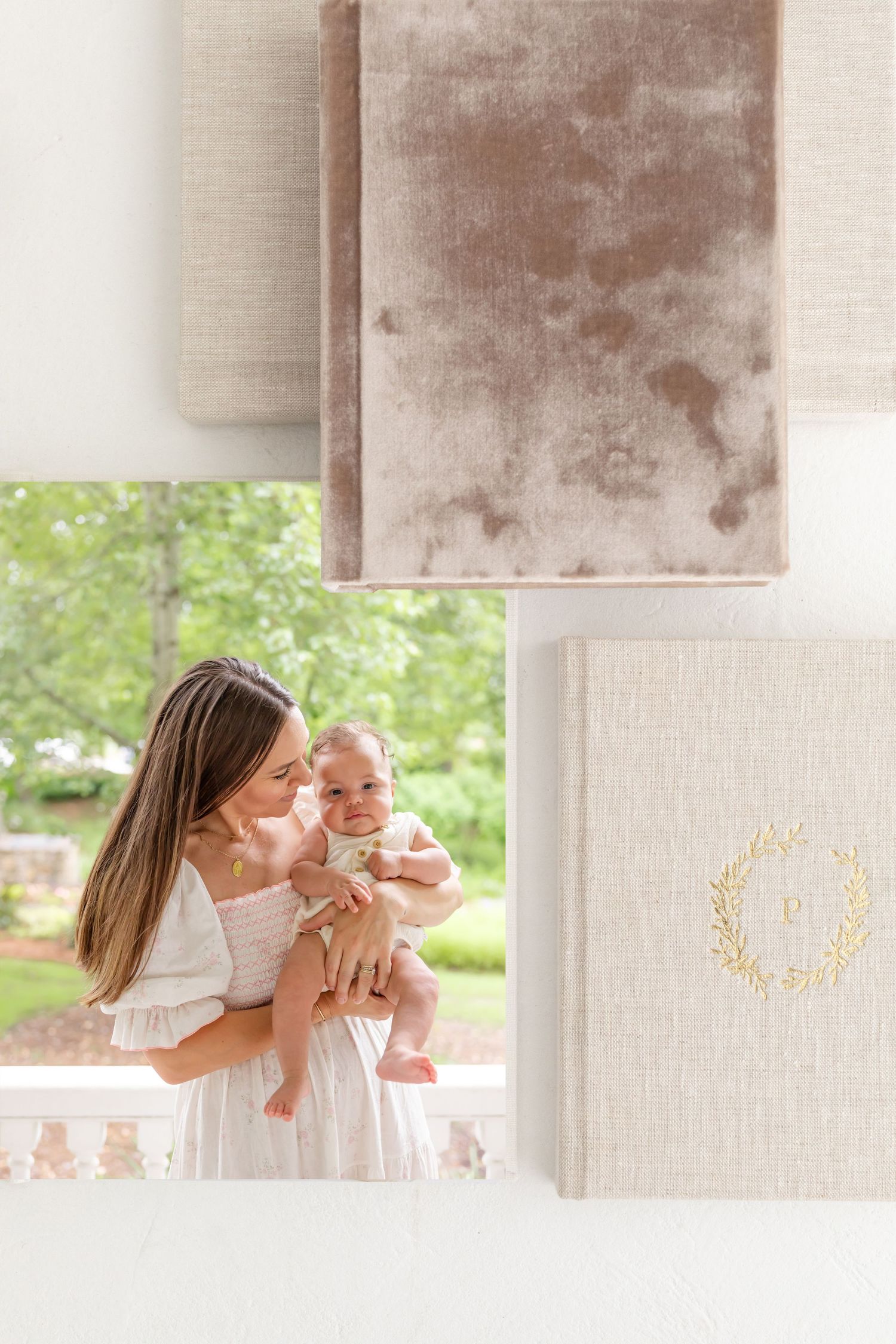Flay of heirloom albums with on open showing an image of a Mather holding her baby against a lush green garden setting.