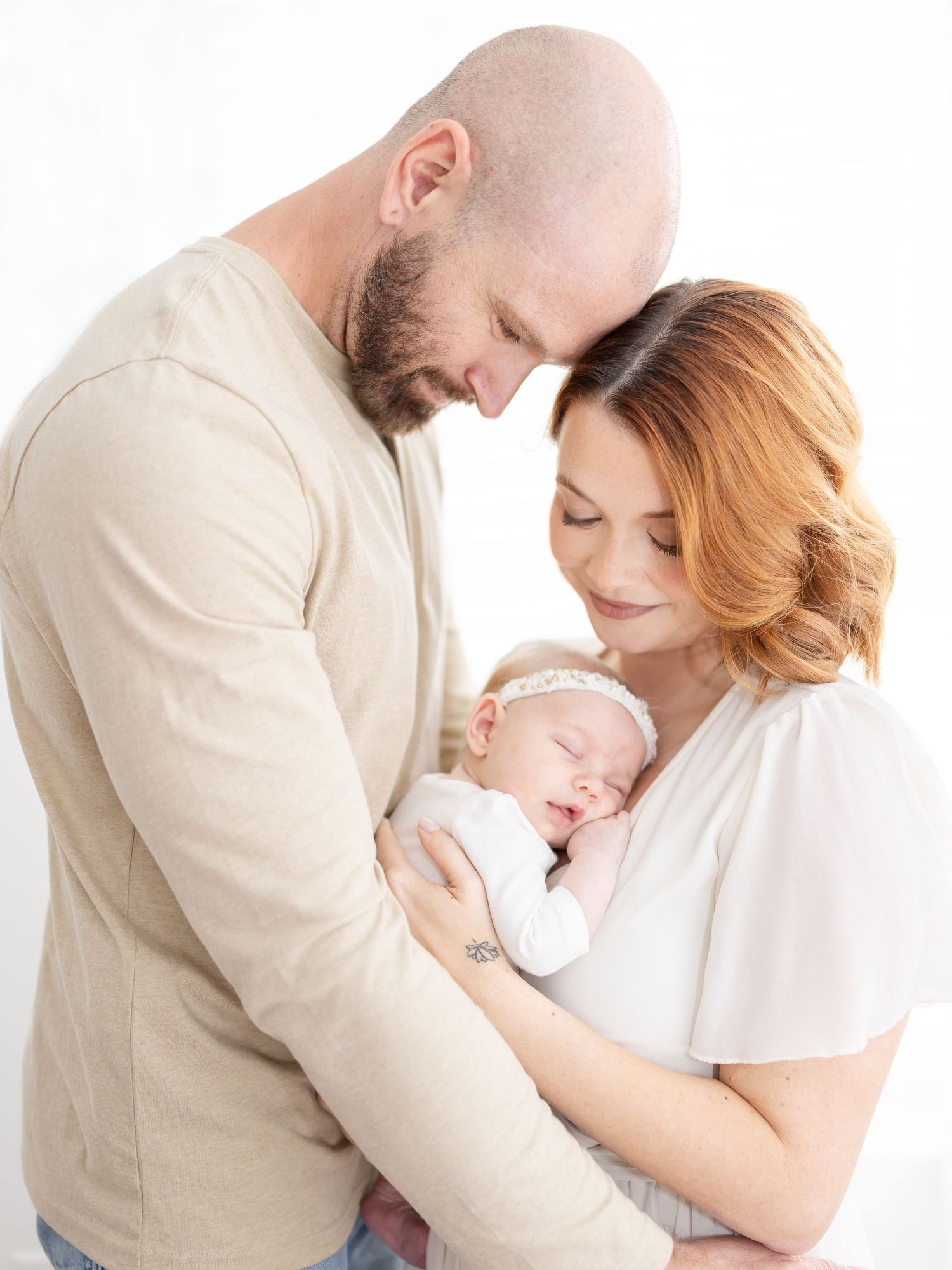 A tender family moment showing parents embracing their newborn in neutral outfits at their Columbus, GA newborn photography session.
