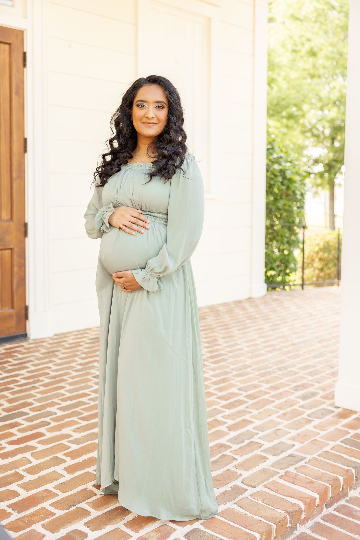 A pregnant mother stands on a brick sidewalk at Old Town Columbus during her Columbus, GA maternity photography session.