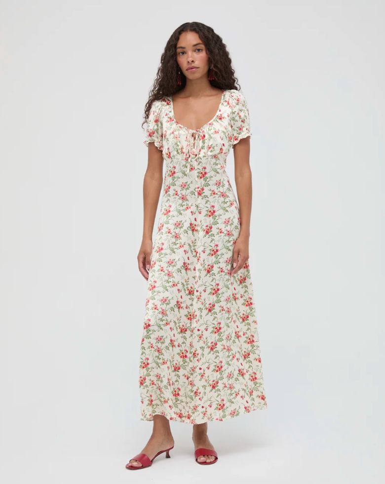 Woman wearing a cream floral maxi dress with short puff sleeves, cinched waist, and red kitten heels.